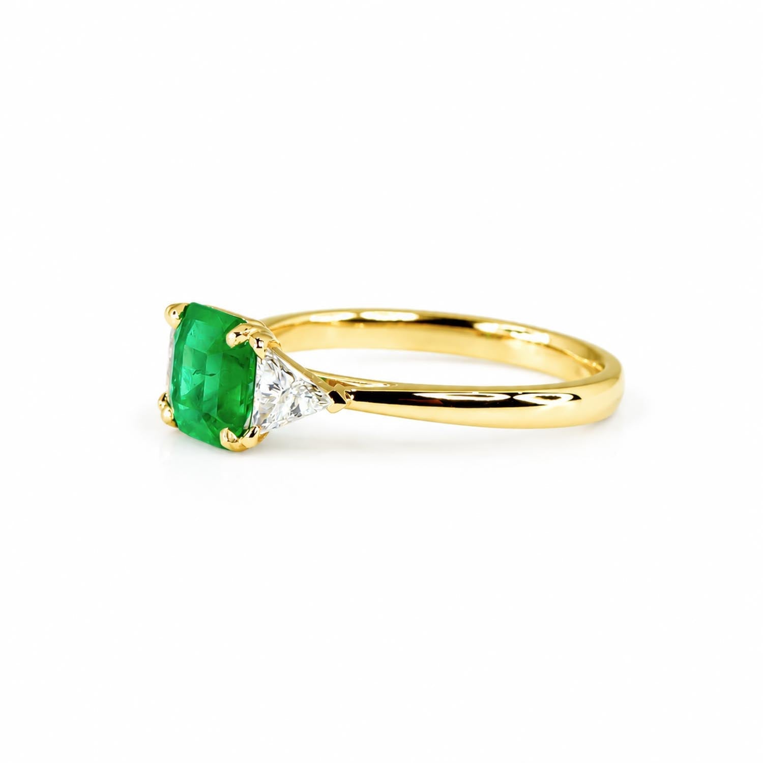 Emerald cut Colombian emerald ring with two trillion cut diamonds in 18K yellow gold