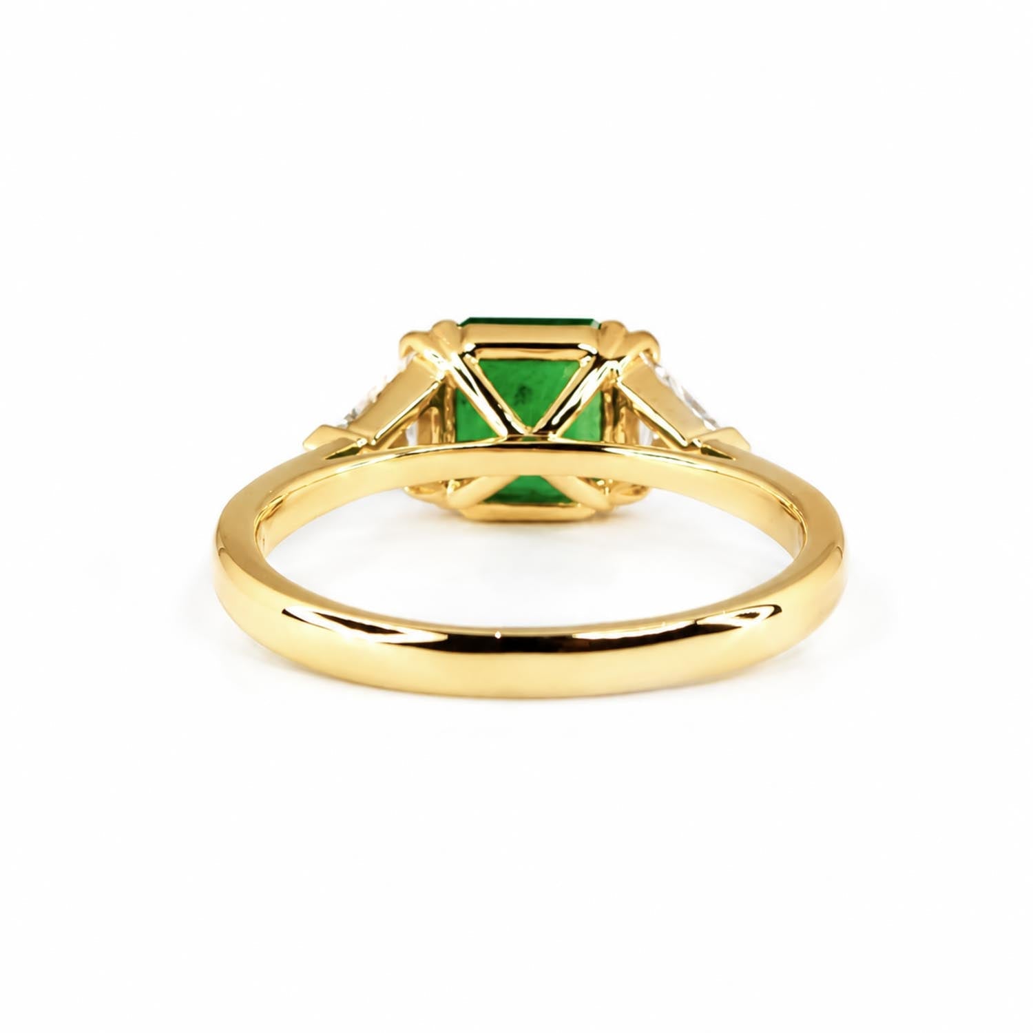 Side view of Colombian emerald and trillion diamond ring in 18K yellow gold