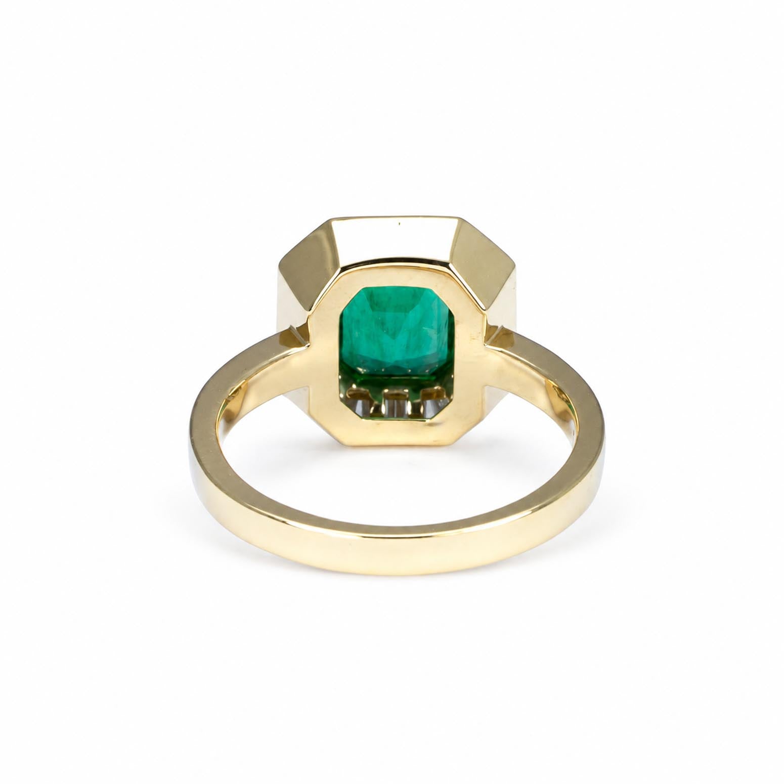 Back view of a  gold ring featuring a  faceted emerald-cut emerald, shown on a clean white background.