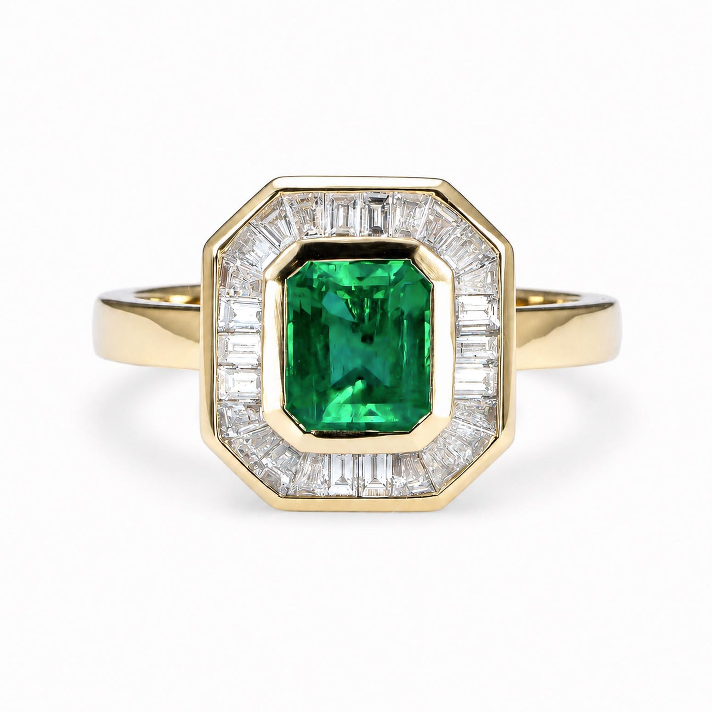A yellow gold ring featuring an emerald-cut natural Colombian emerald in the center, surrounded by a halo of baguette-cut diamonds, set against a plain white background.