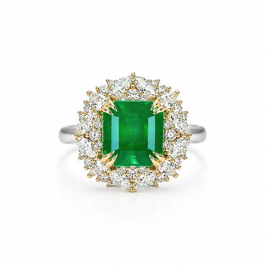 A halo ring featuring an emerald-cut Colombian emerald center stone surrounded by a double halo of round and marquise and pear-cut diamonds in yellow gold and white gold settings, shown on a clean white background.