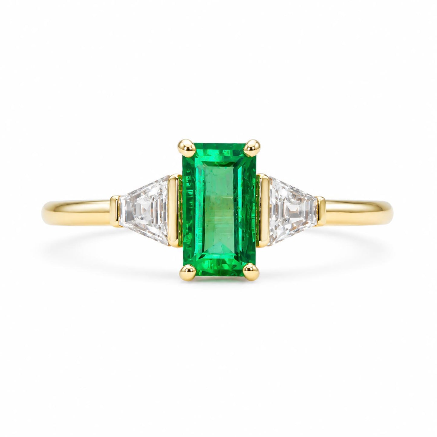 A yellow gold ring featuring a rectangular emerald-cut Colombian emerald in the center, flanked by two tappered baguette-cut diamonds on a clean white background.