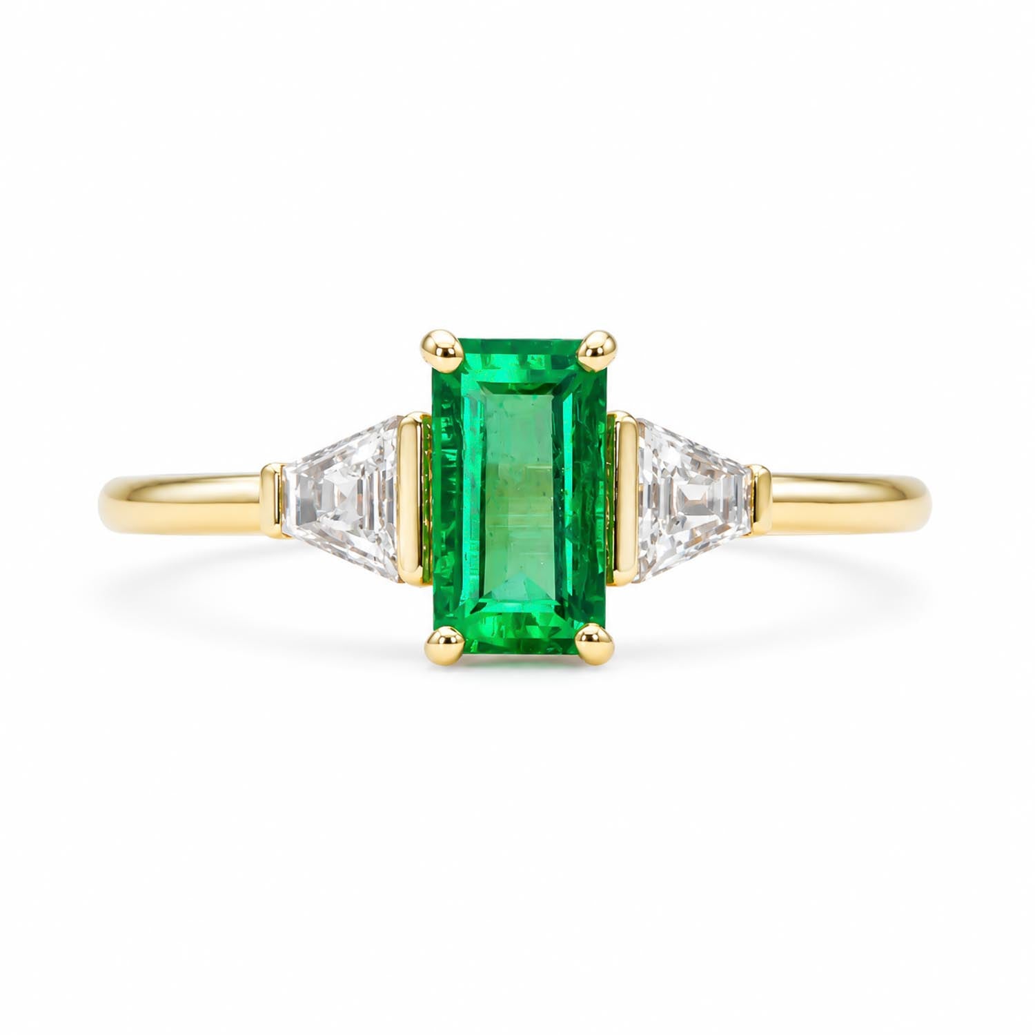 A yellow gold ring featuring a rectangular emerald-cut Colombian emerald in the center, flanked by two tappered baguette-cut diamonds on a clean white background.