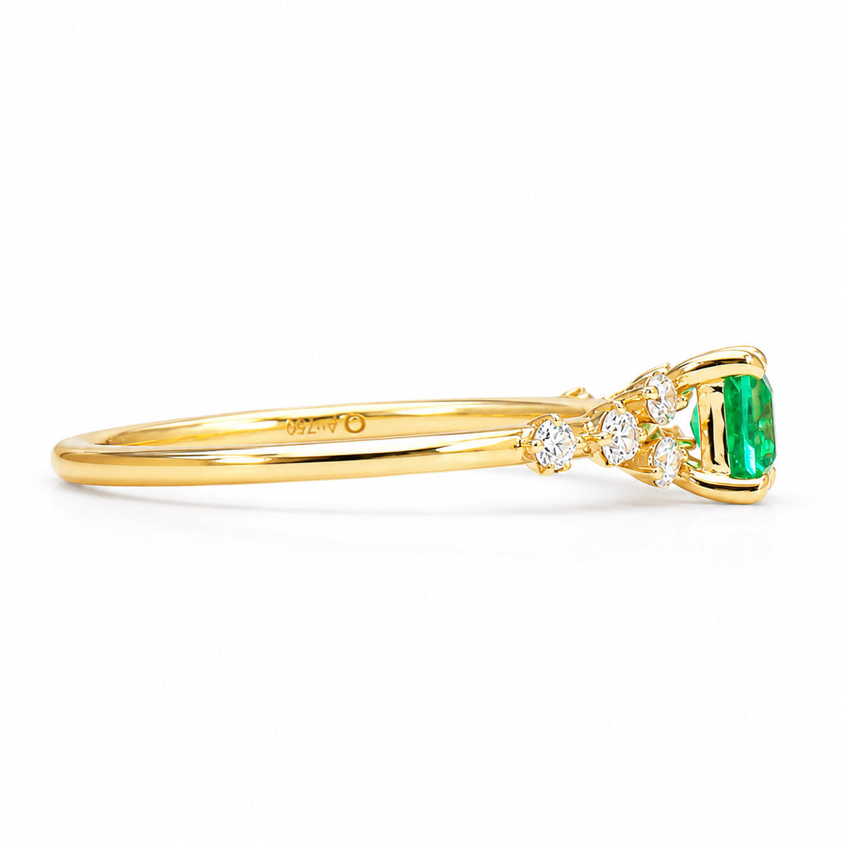 profile view of a gold ring with a Colombian emerald at its centre and side round diamonds on a white background