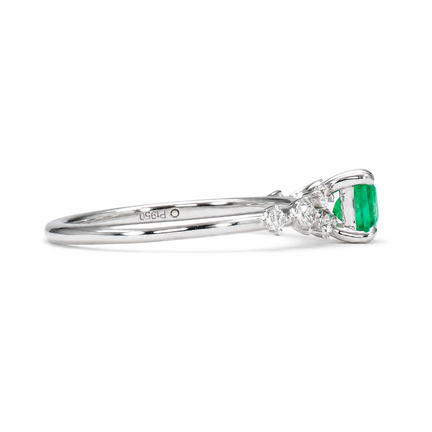 A platinum emerald and diamond ring featuring an emerald cut Colombian emerald center stone and small round diamonds on the shoulders, shown in profile against a white background.