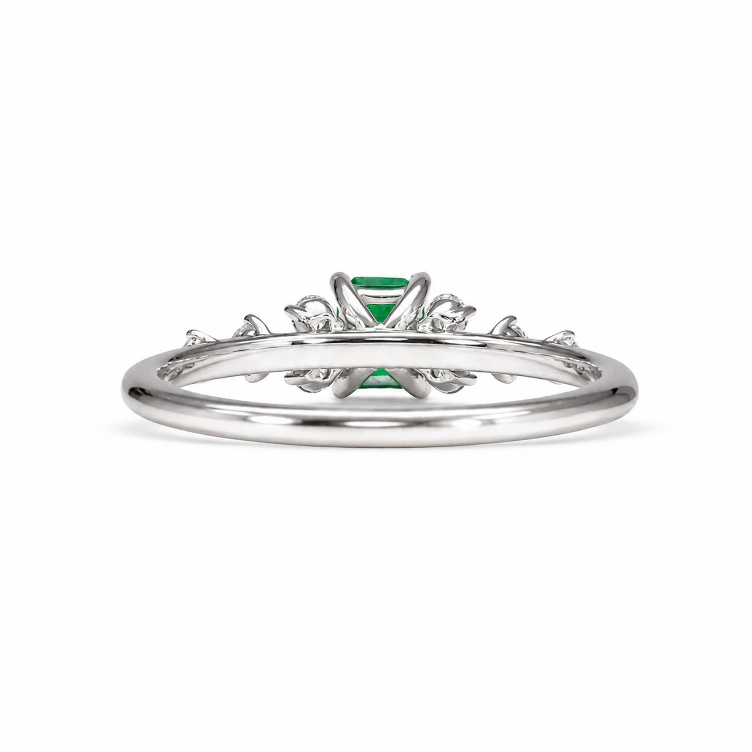 Back view of a platinum ring featuring a central Colombian emerald gemstone and delicate side accent diamonds, shown on a plain white background.
