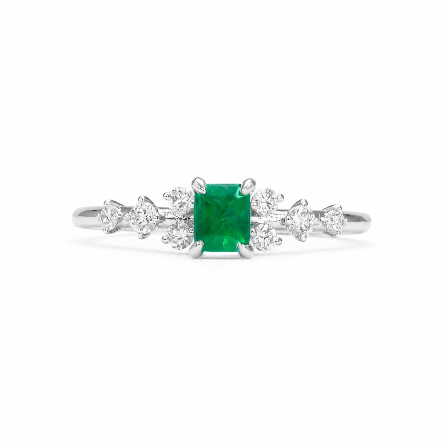 A platinum ring featuring an emerald-cut Colombian emerald center stone and round-cut diamonds on each side, set against a plain white background.