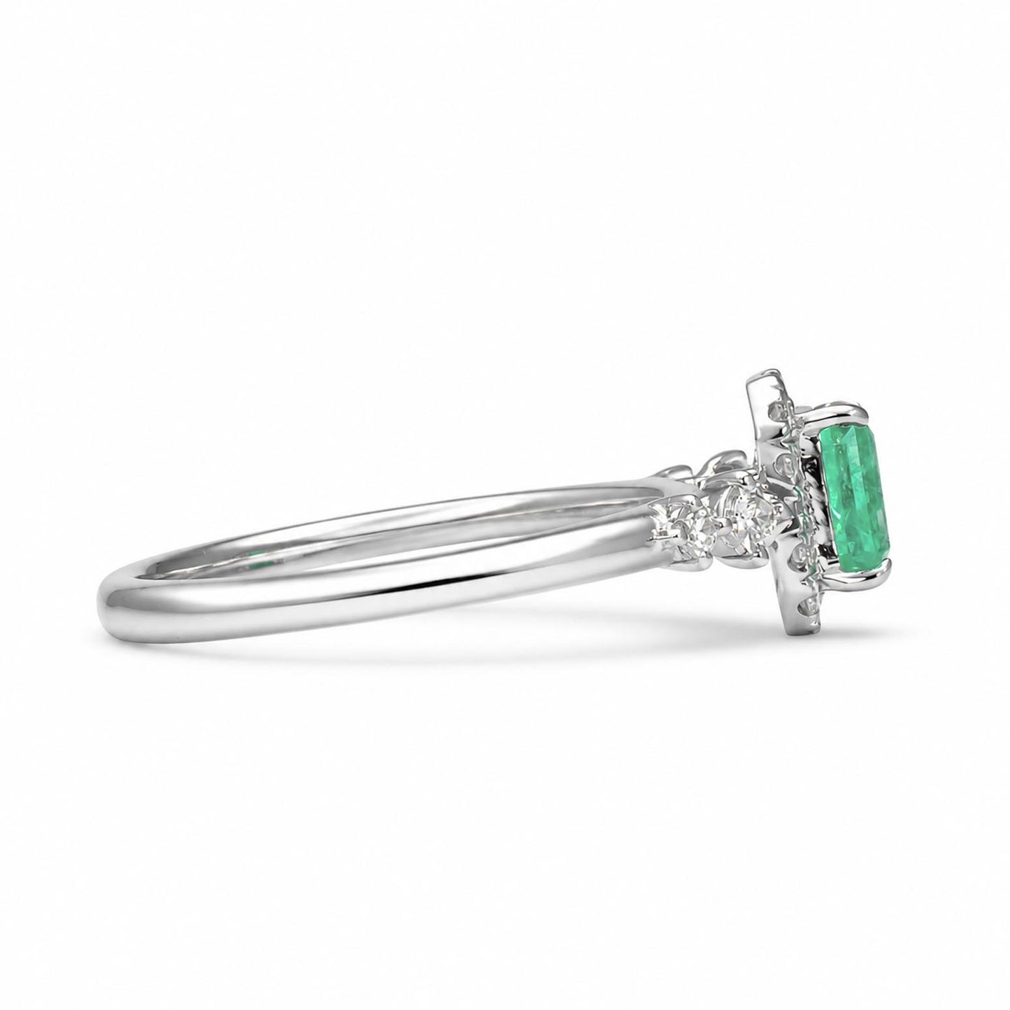 A platinum ring featuring a rectangular emerald-cut Colombian emerald and accent diamonds, shown in profile against a clean white background.