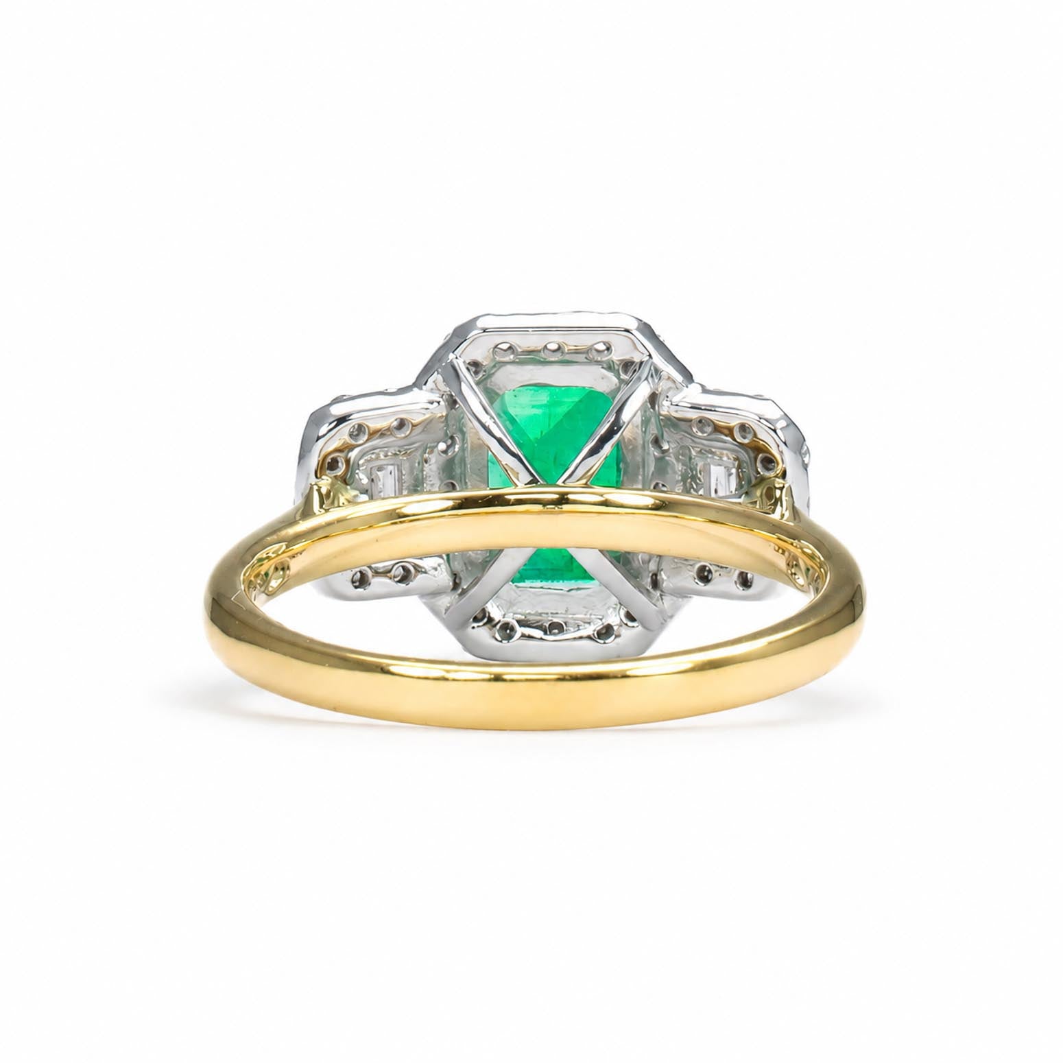 A yellow gold ring with a platinum setting featuring a central Colombian emerald and diamond accent stones, shown on a white background.