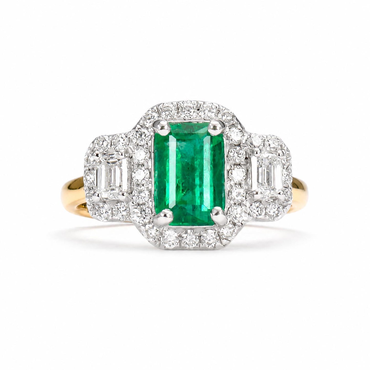 An Art Deco style emerald-cut Colombian emerald ring set in yellow gold and platinum with diamond accents, shown on a clean white background.