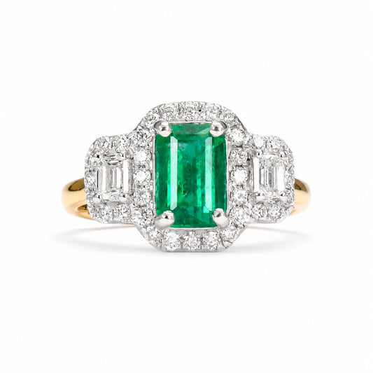 An Art Deco style emerald-cut Colombian emerald ring set in yellow gold and platinum with diamond accents, shown on a clean white background.