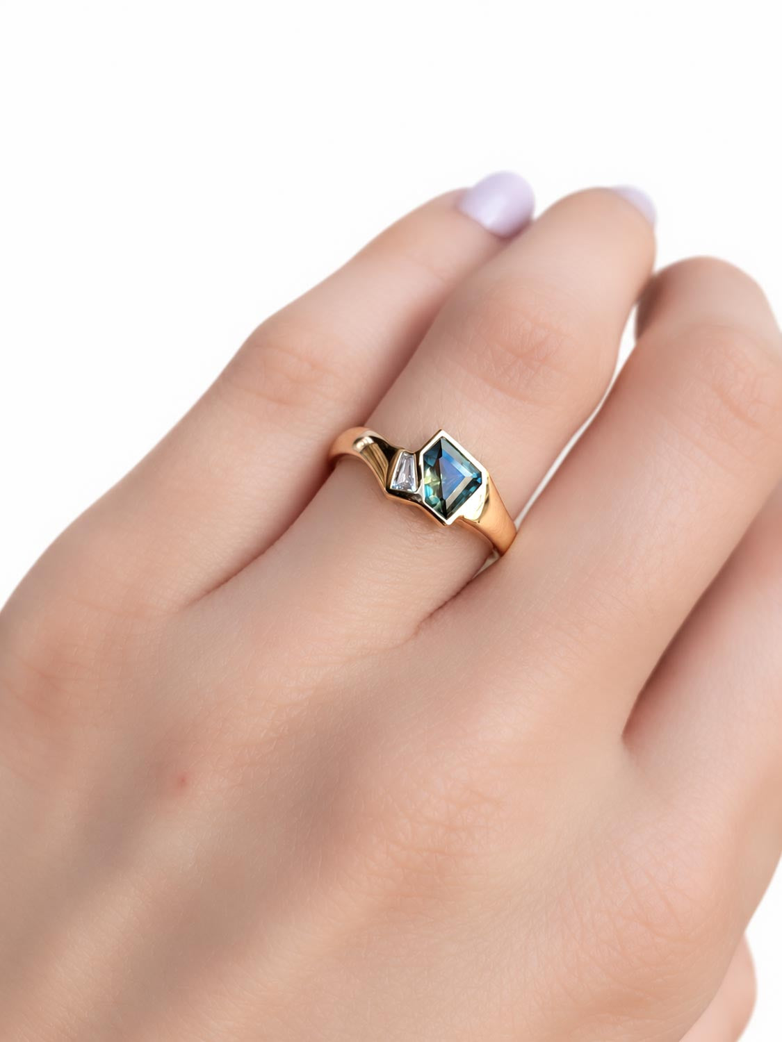 Close detail of the natural teal sapphire centre stone in gold