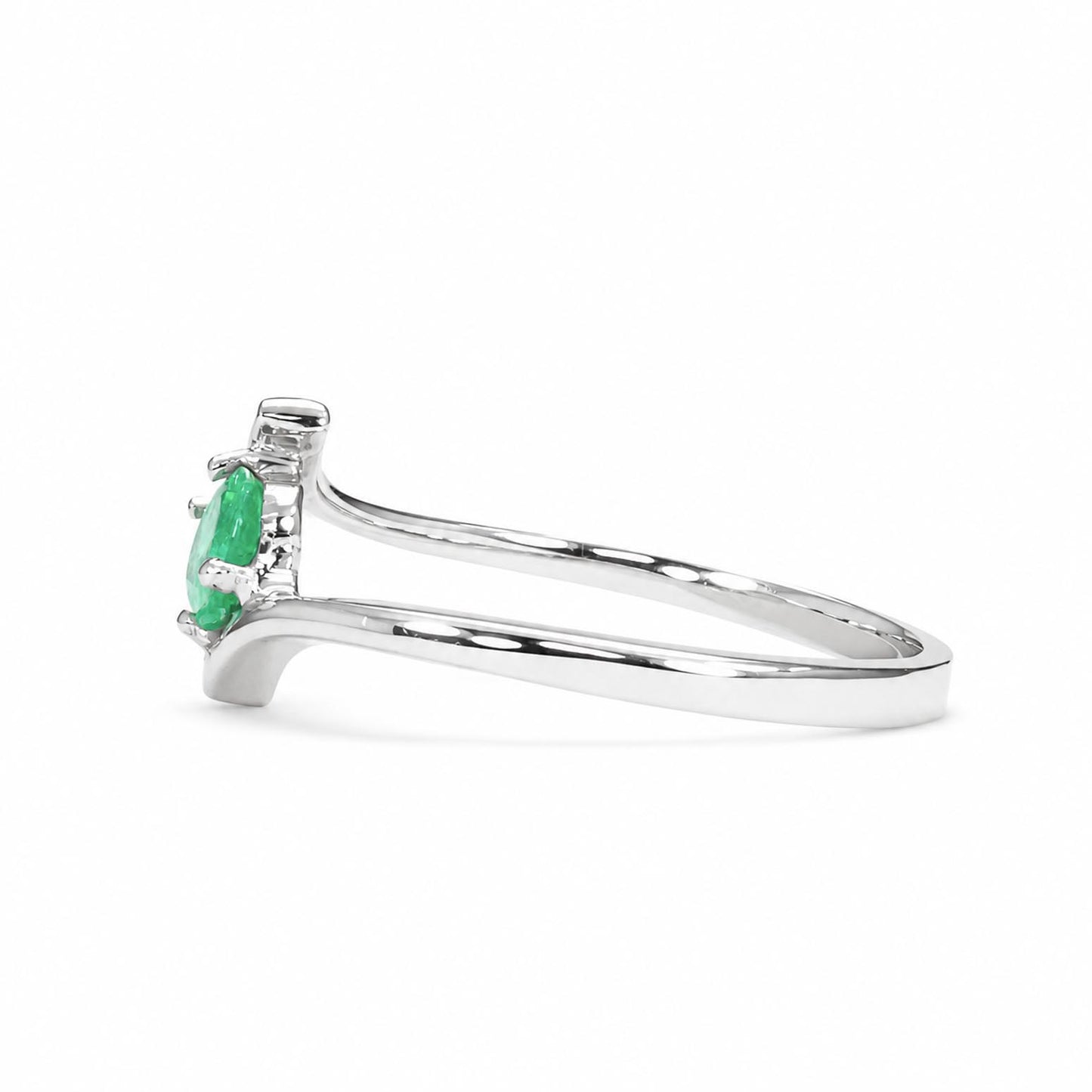 Side view of a white gold ring geaturinf an oval Colombian emerald an centre stone on a white background