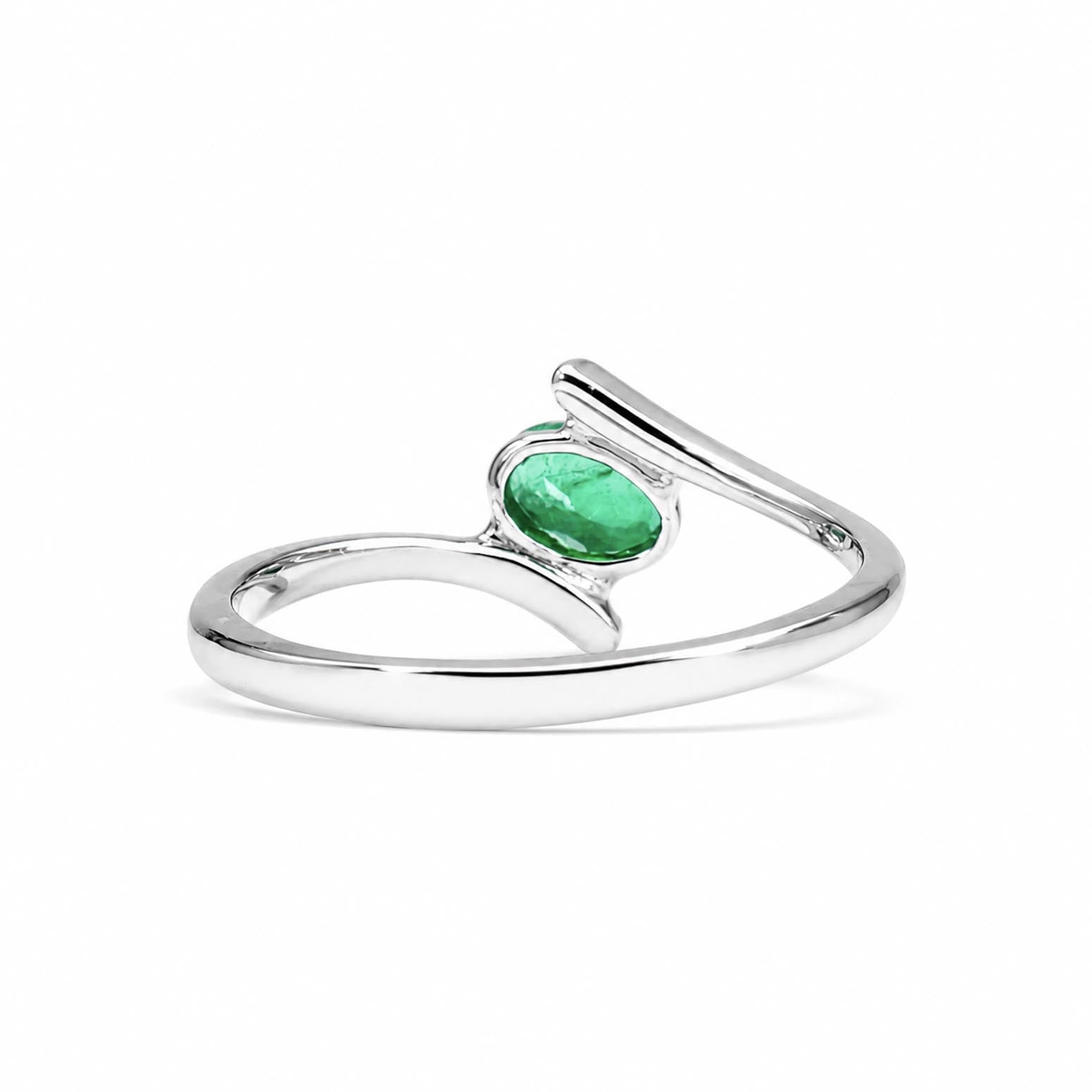 back view of a white gold ring featuring an oval-cut Colombian emerald offset to an angle on a white background
