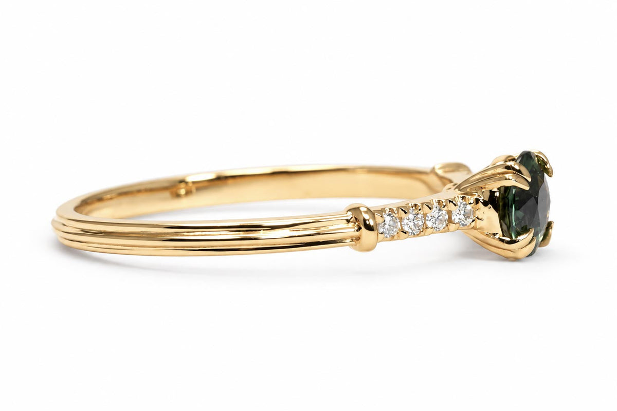Teal sapphire ring with diamond band in 18K yellow gold shown at an angle