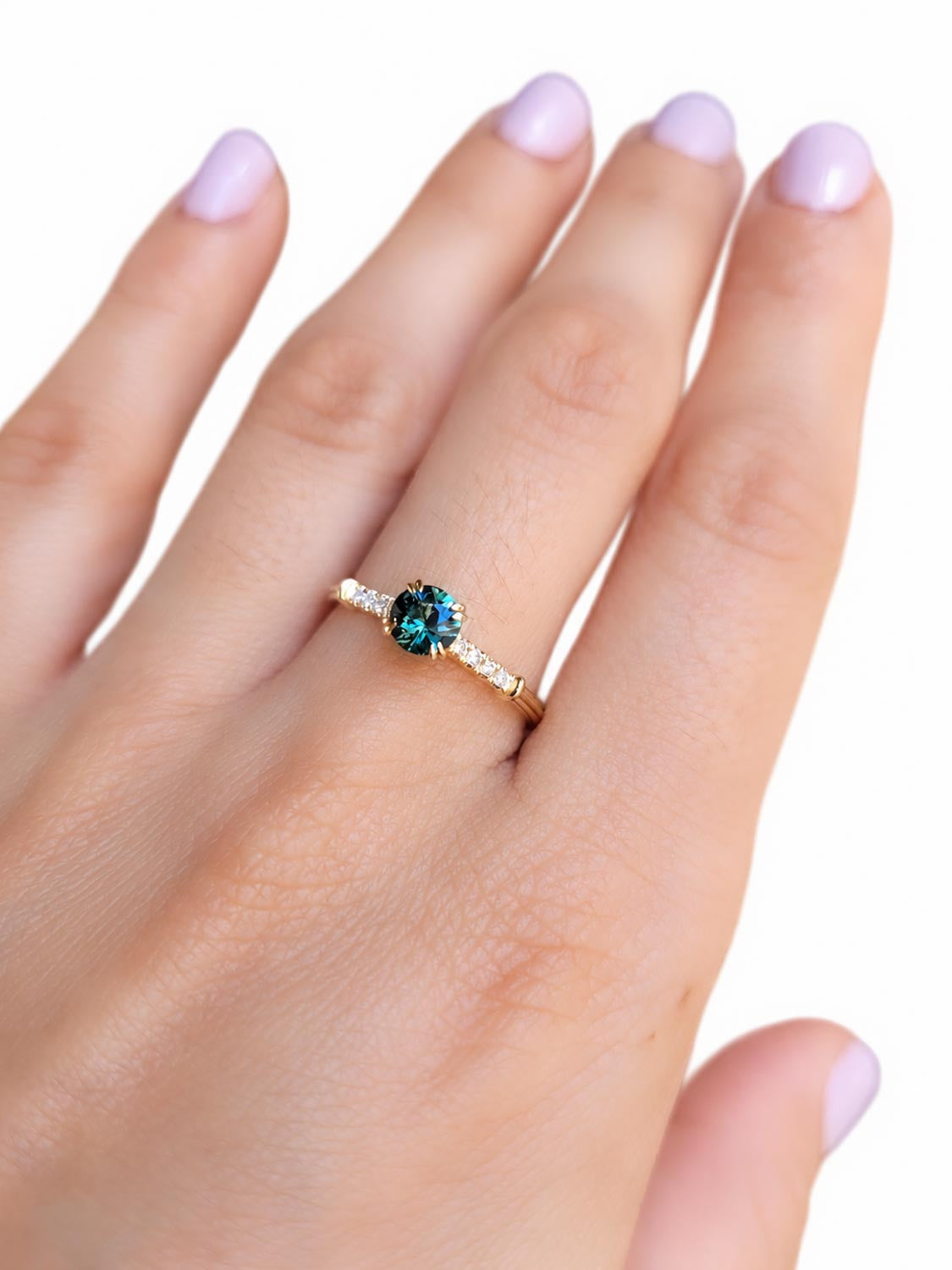 Side profile of the round teal sapphire and diamond band ring in gold