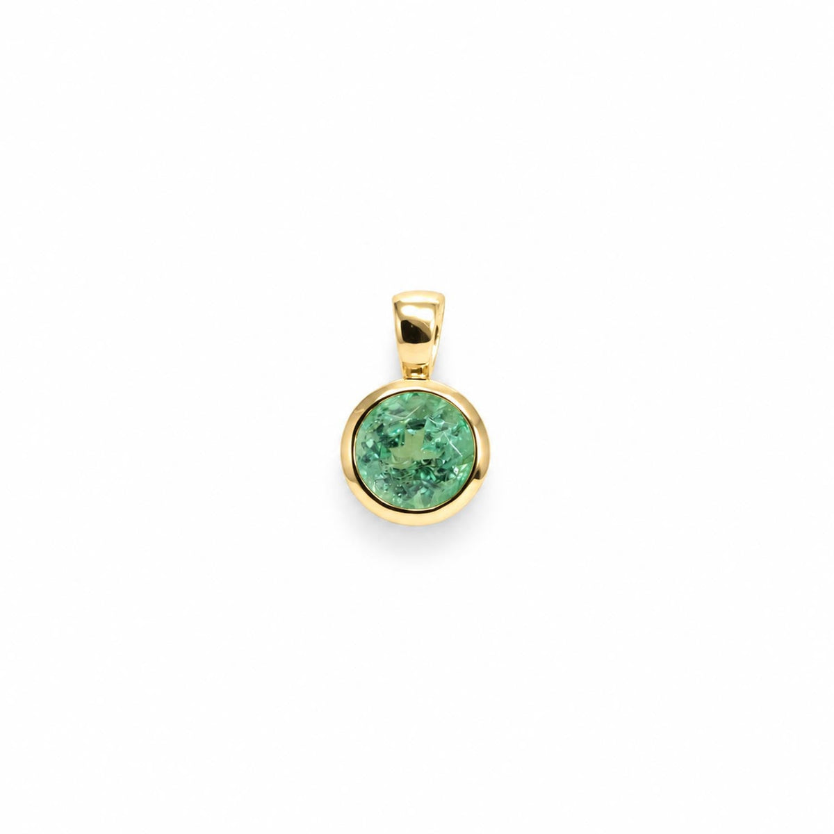 Bezel set Colombian emerald pendant in 18K yellow gold shown at an angle