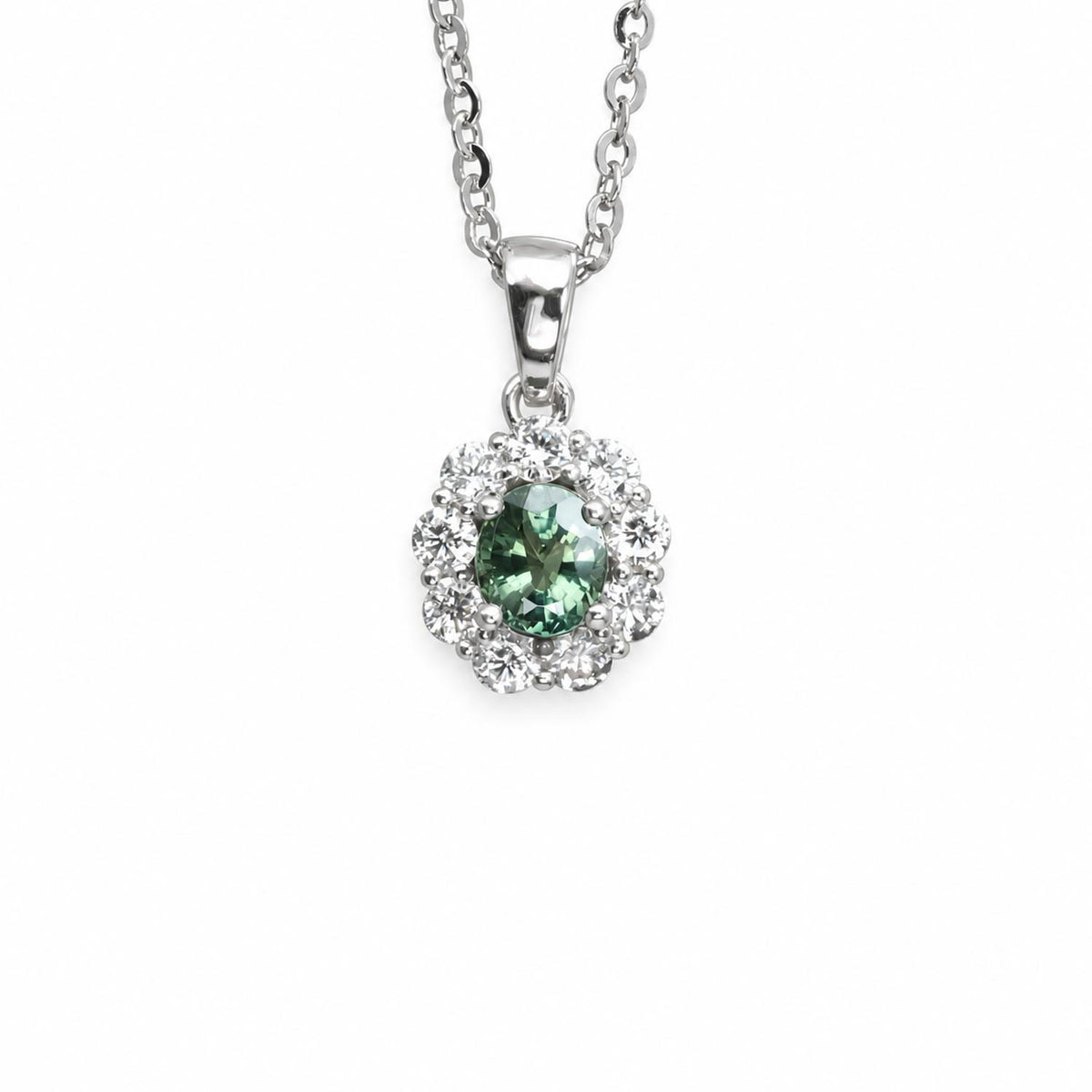 A platinum pendant necklace featuring an oval green alexandrite surrounded by a halo of diamonds, suspended from a silver chain on a white background.