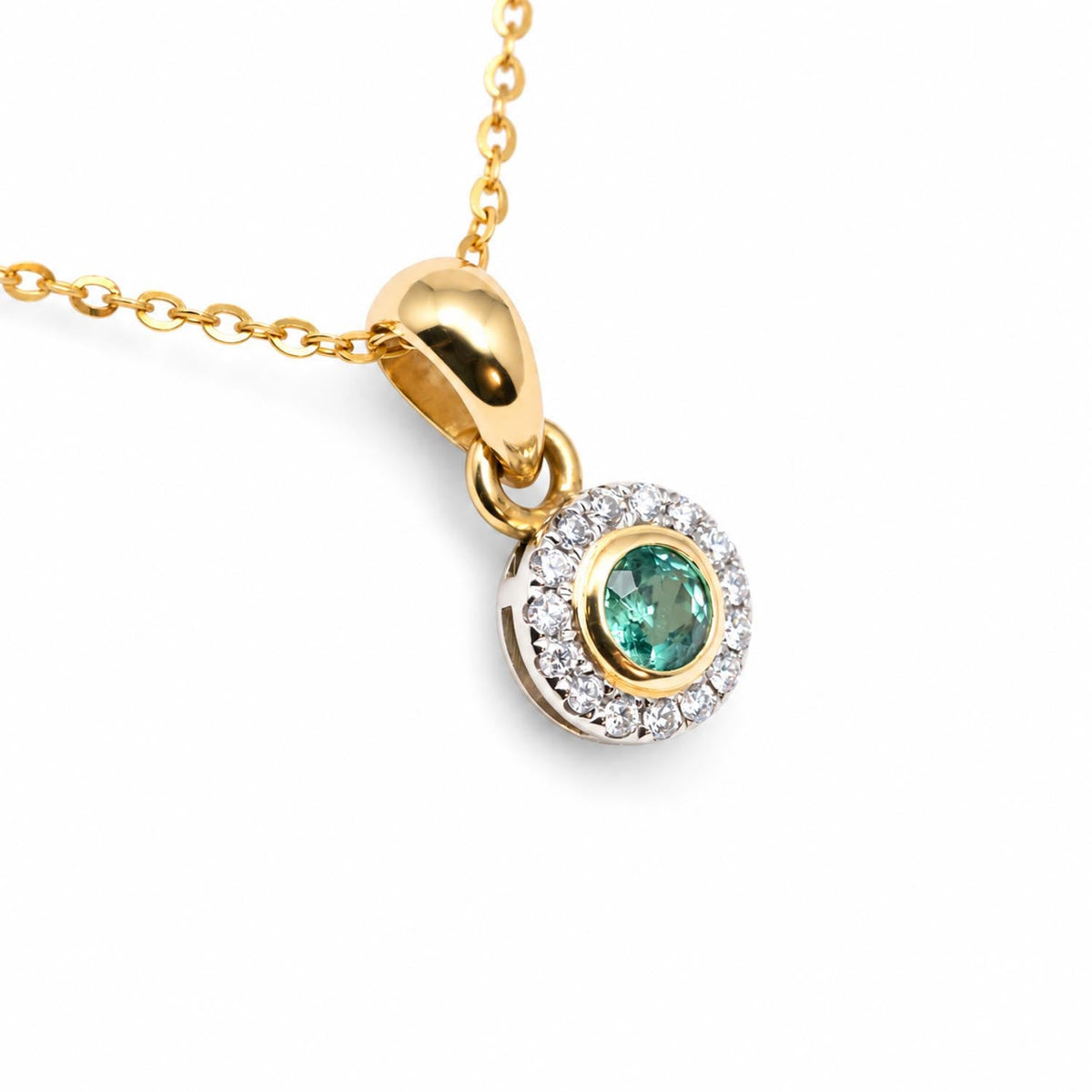 Colombian emerald diamond halo pendant in two tone gold shown at an angle