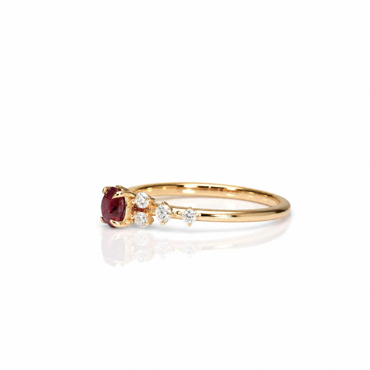 side view of a ruby and diamonds ring set in 18K yellow gold shown on a white background