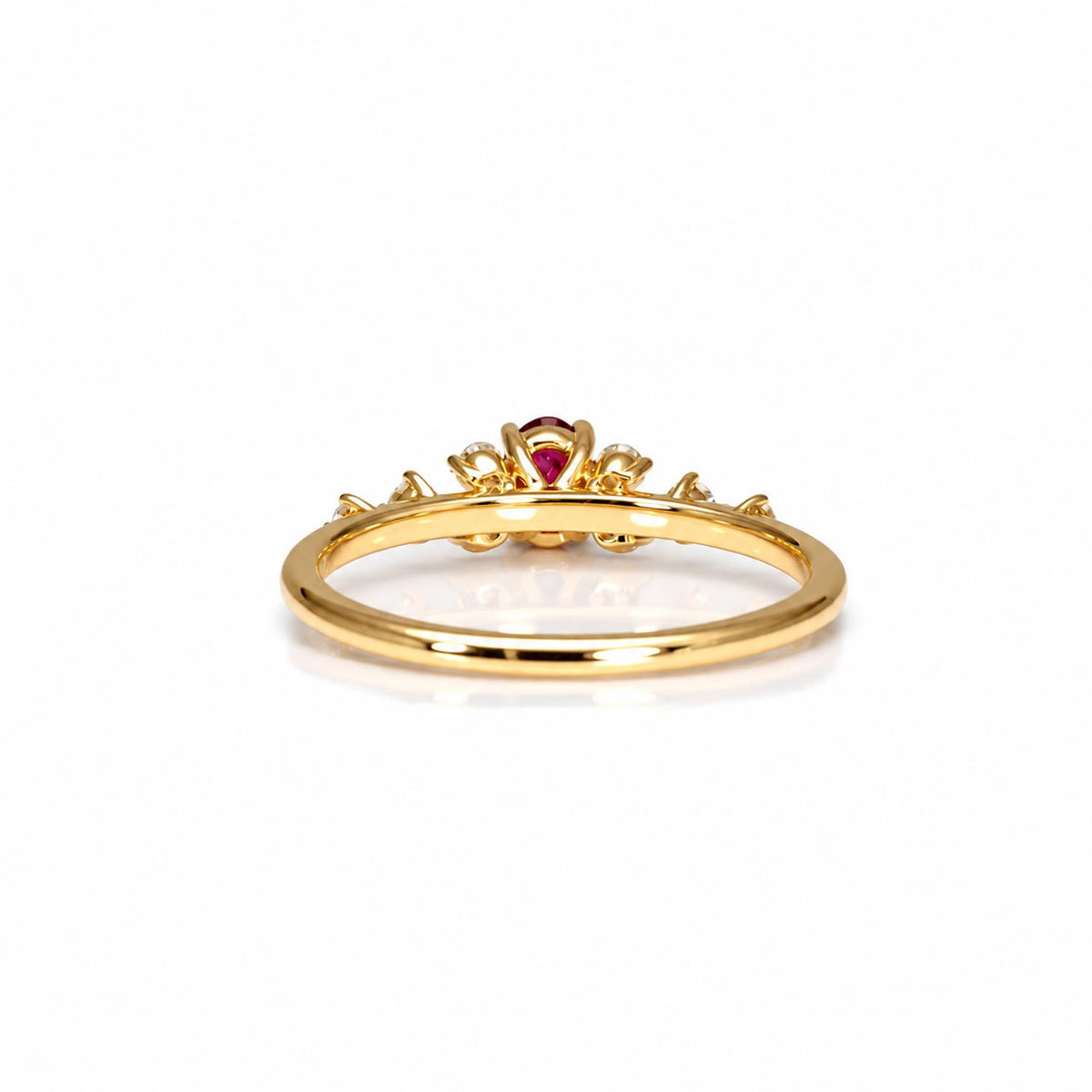 A gold ring with a small natural ruby gemstone in the center, photographed on a clean white background.
