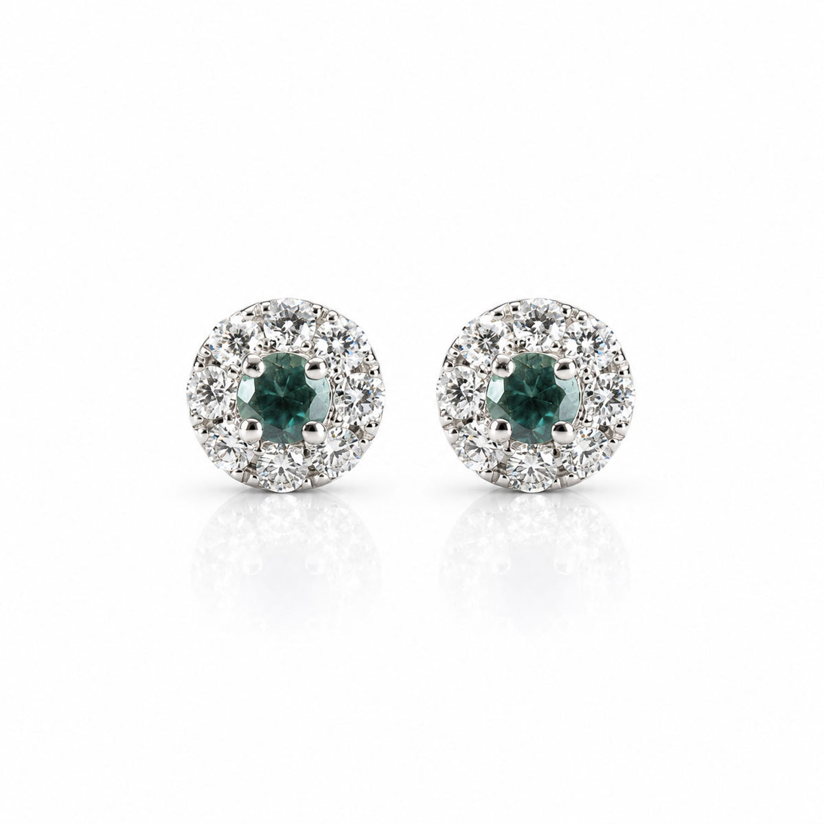 a pair of platinum earrings featuring alexandrite centres and a halo of diamonds, shown on a white background with a soft reflection