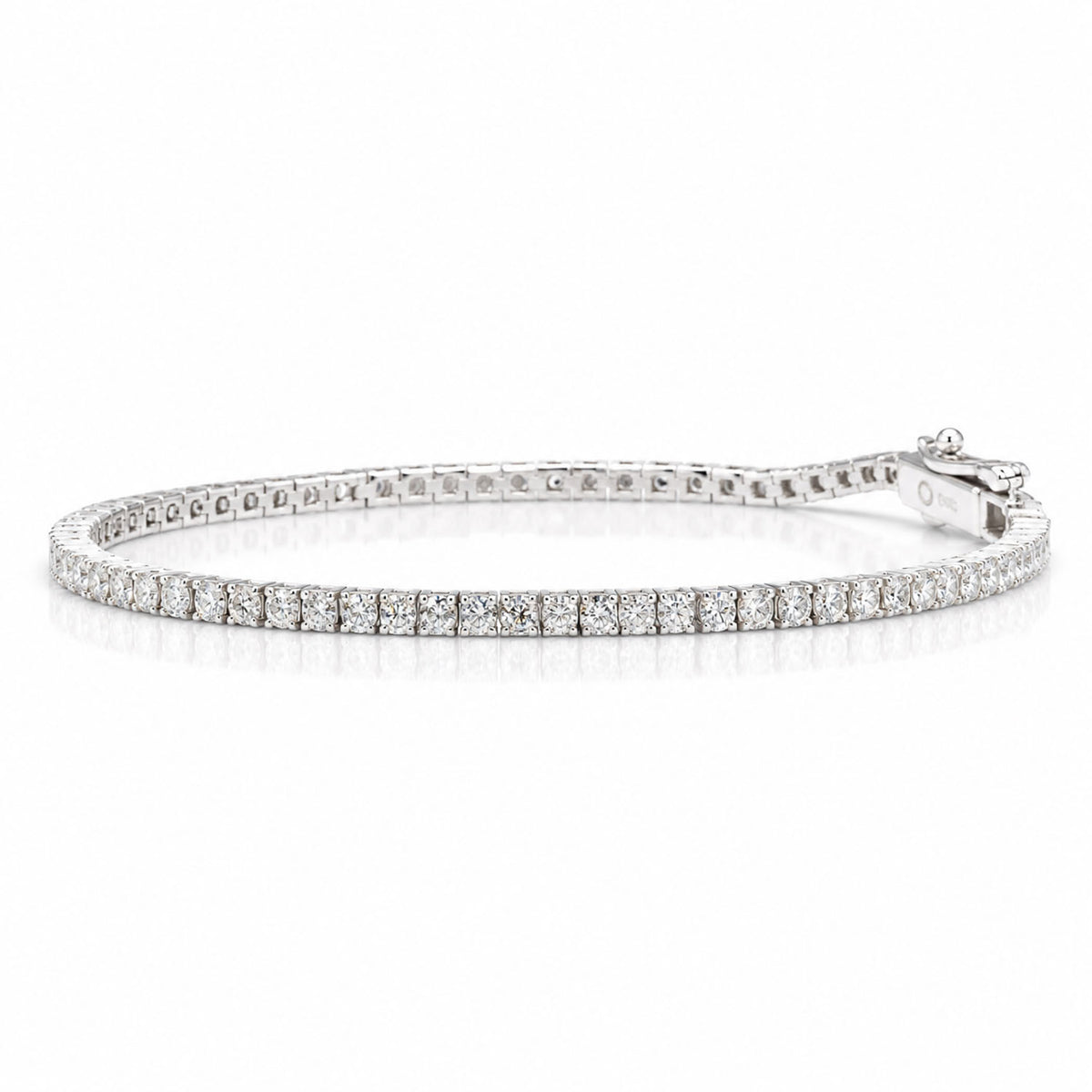 A platinum tennis bracelet with round brilliant cut diamonds and a box clasp with a safety latch shown on a white background with a soft reflection
