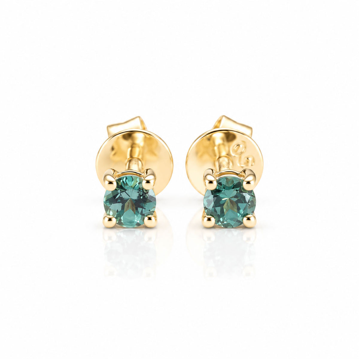 A pair of 18K yellow gold stud earrings with natural alexandrites as centre stones shown in a white background with a soft reflection