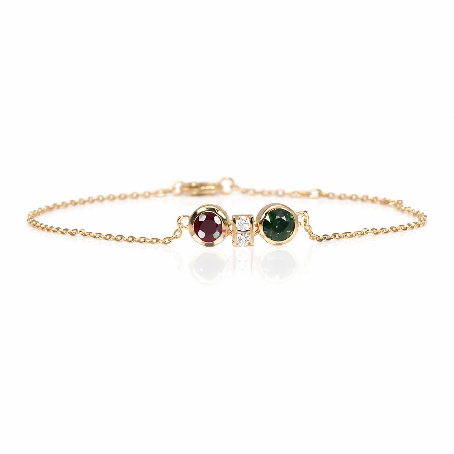 A delicate gold chain bracelet featuring two round bezel-set gemstones, one natural ruby and one Australian teal sapphire, separated by accent diamonds shown on a white background.