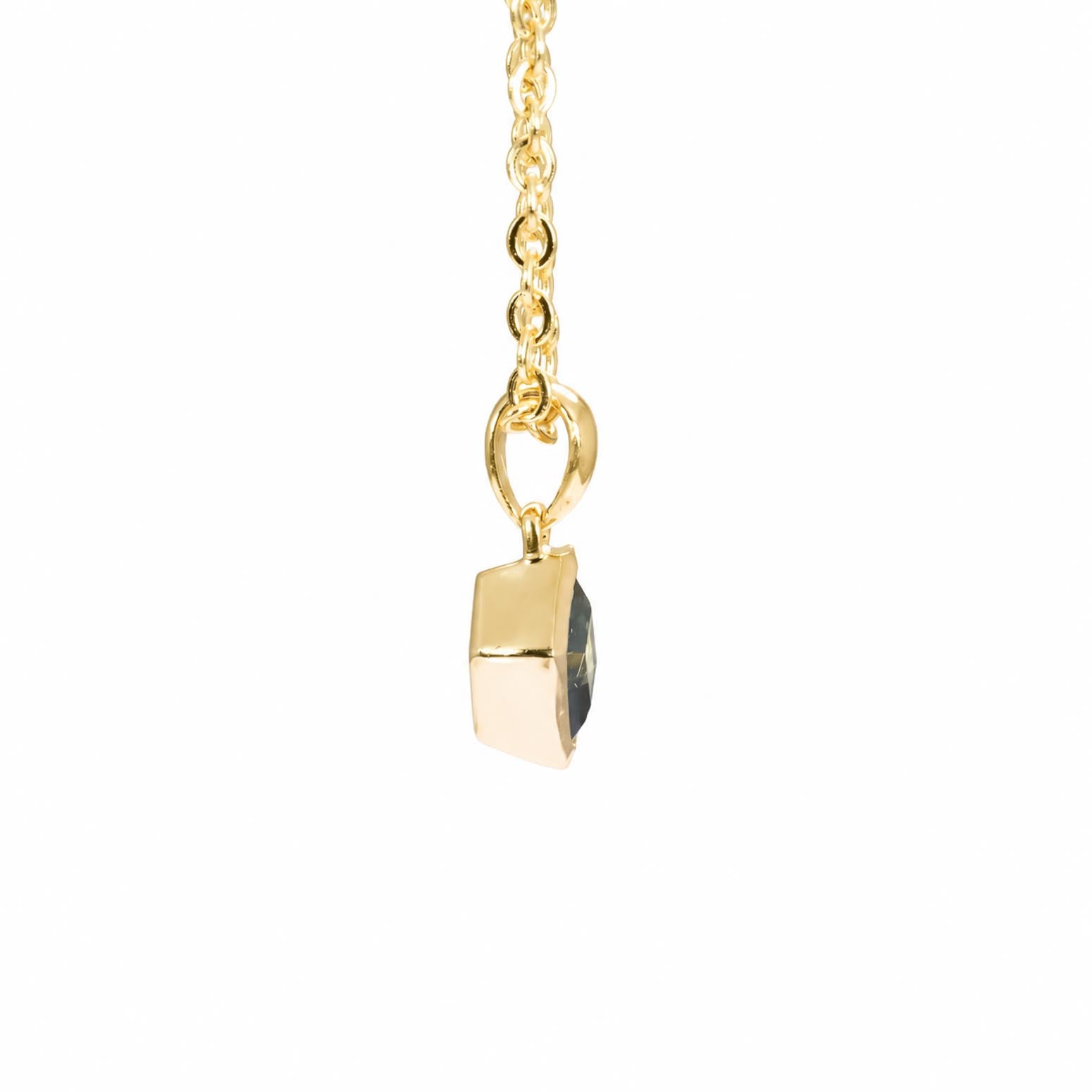 A gold pendant necklace featuring a small, faceted freeform teal sapphire, suspended from a delicate gold chain against a solid white background.