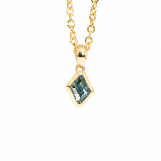A gold chain necklace with a small diamond-shaped bezel setting holding a teal sapphire, shown against a plain white background.