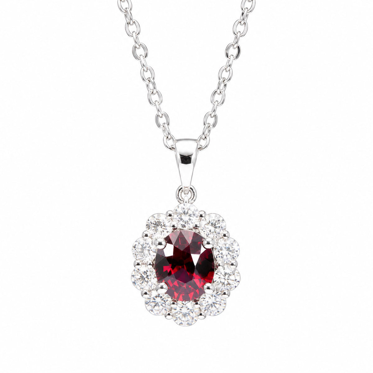a platinum pendant with a natural oval cut ruby surrounded by a halo of round diamonds attached to a silver chain on a white background