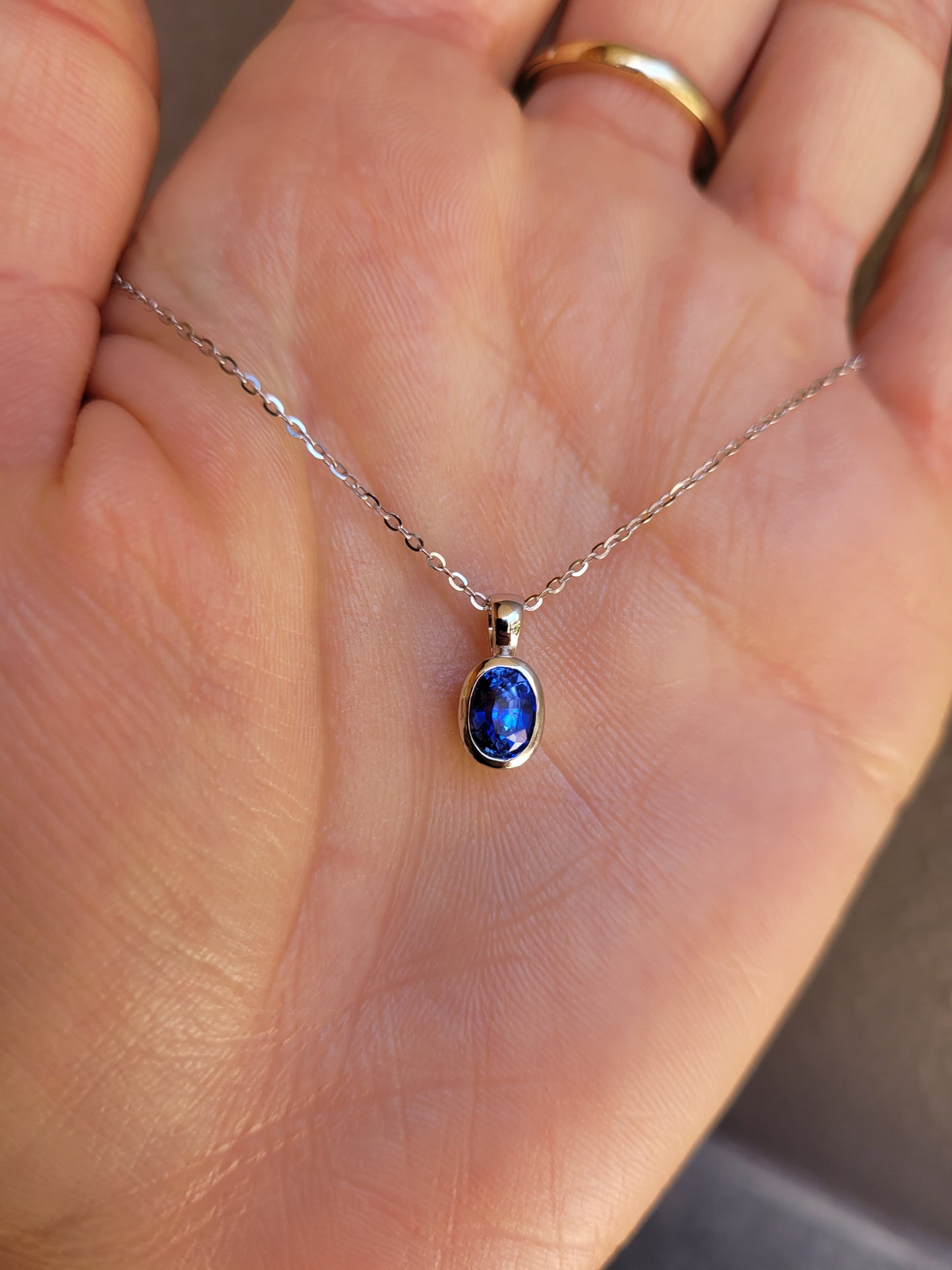 Necklace with a blue pendant held in a hand