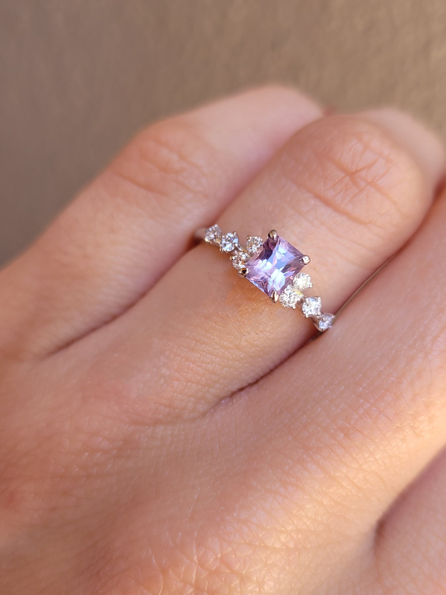 view on hand of Platinum pink sapphire ring with natural diamonds in gray background