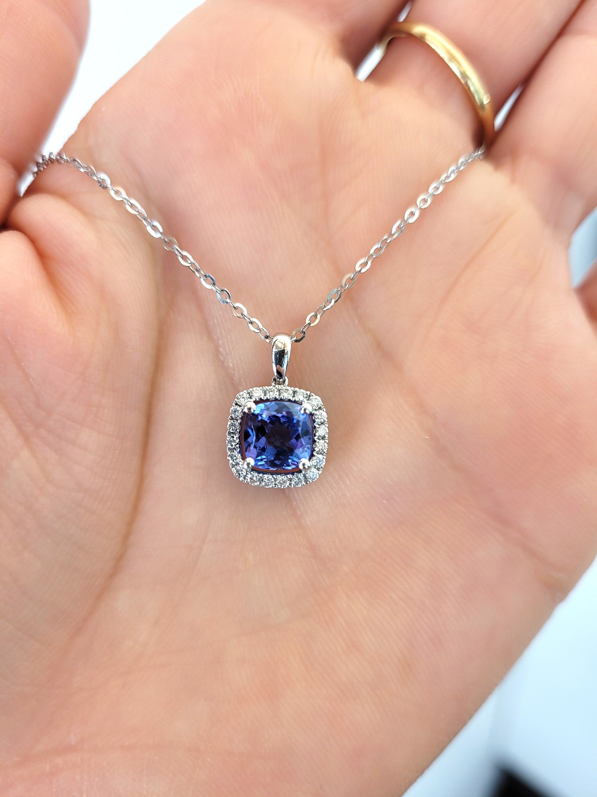 photo on hand of Natural tanzanite diamond pendant in white gold in gray background