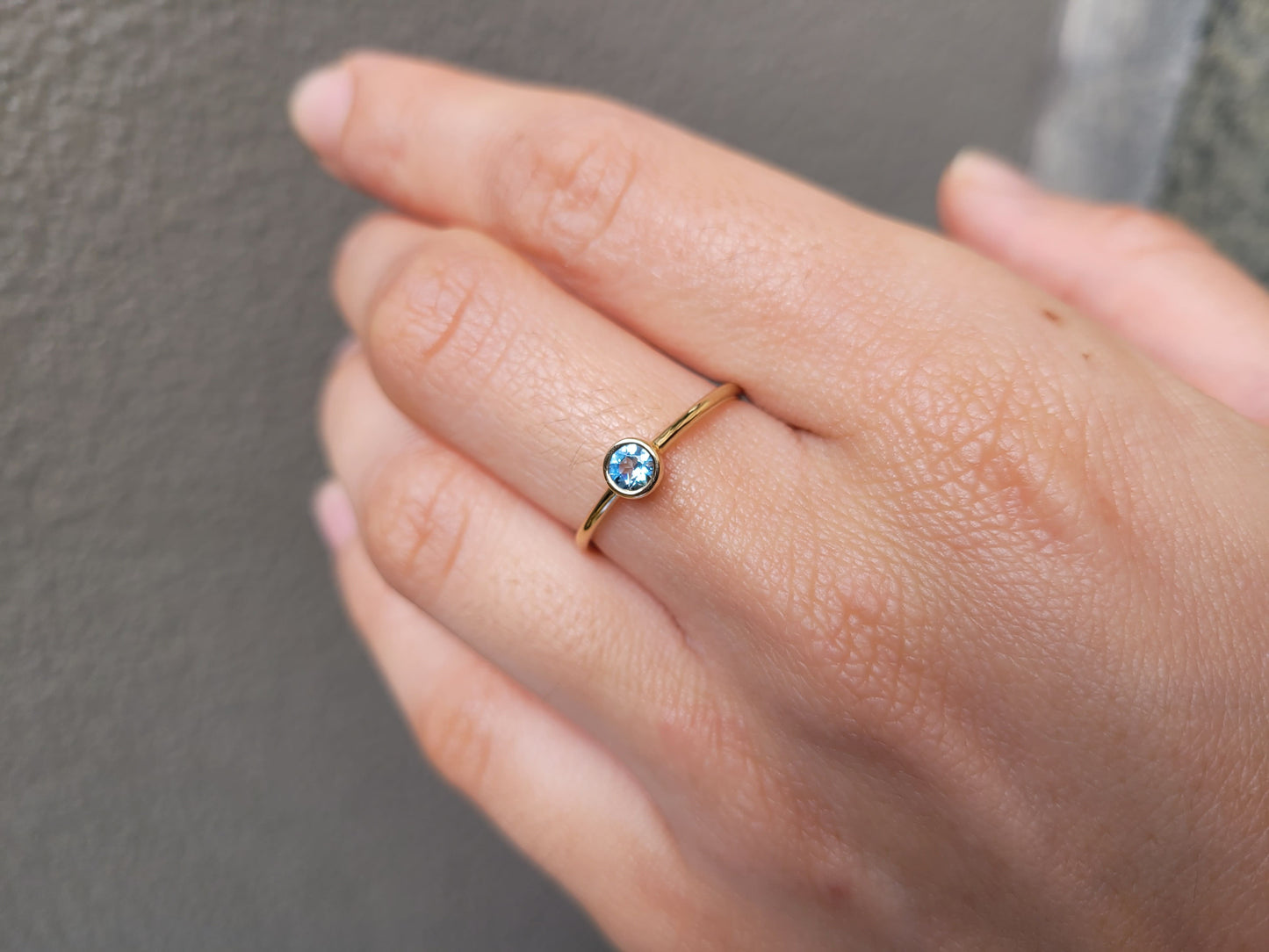 photo on hand of aquamarine yellow gold ring in gray background