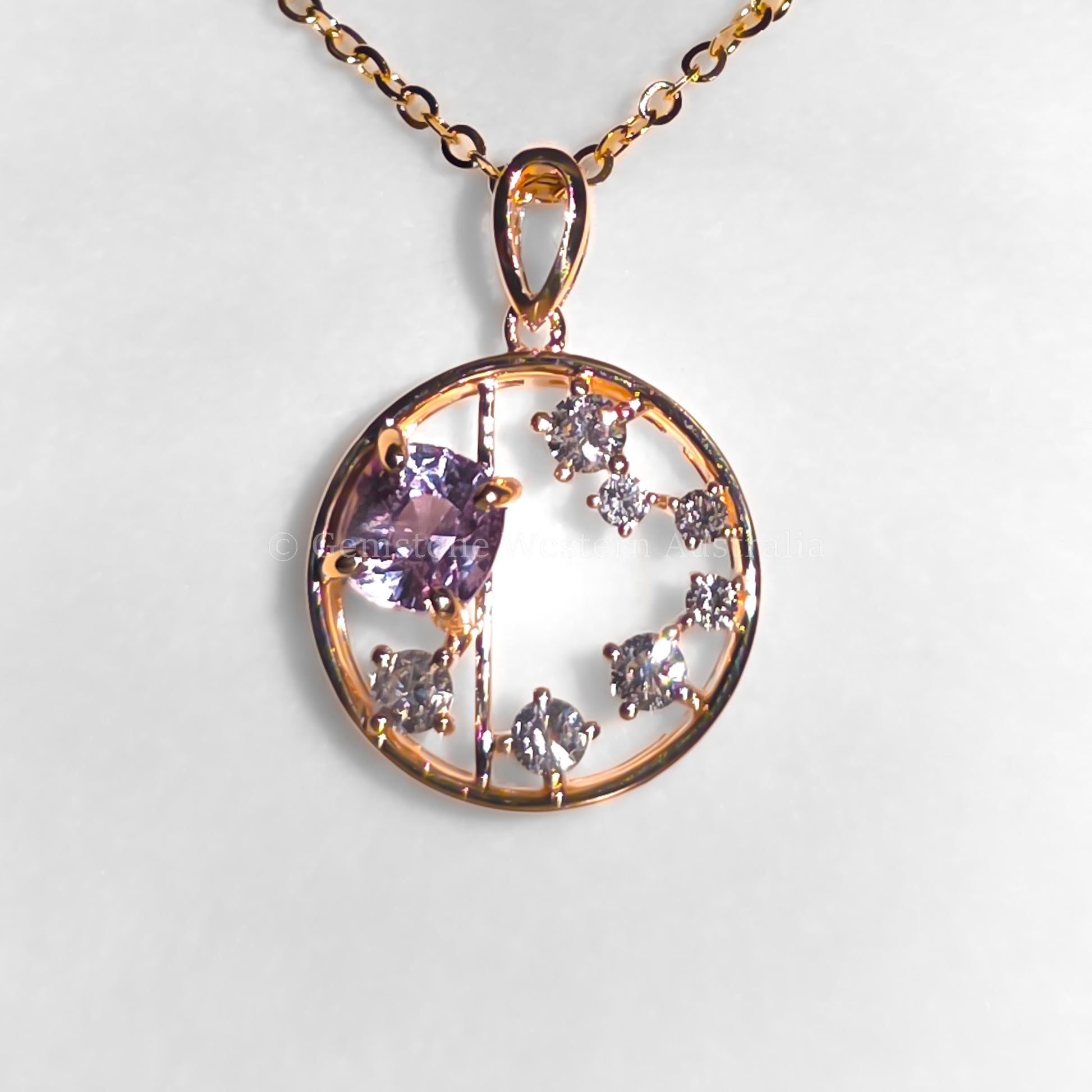 photo of colour shift of open circle gold pendant with alexandrite gemstone and small diamonds on a light gray background