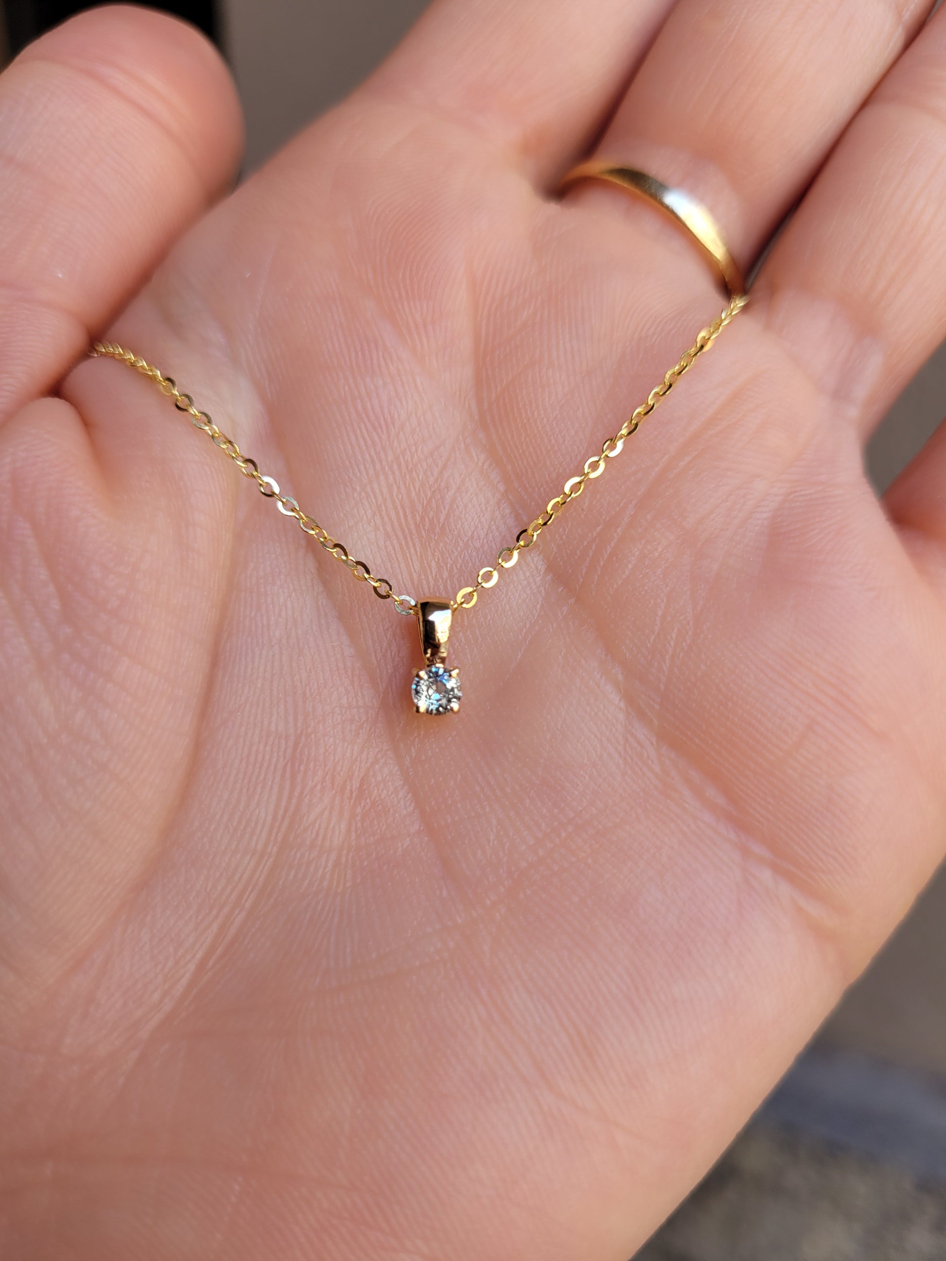 photo on hand of yellow gold alexandrite pendant in gray background