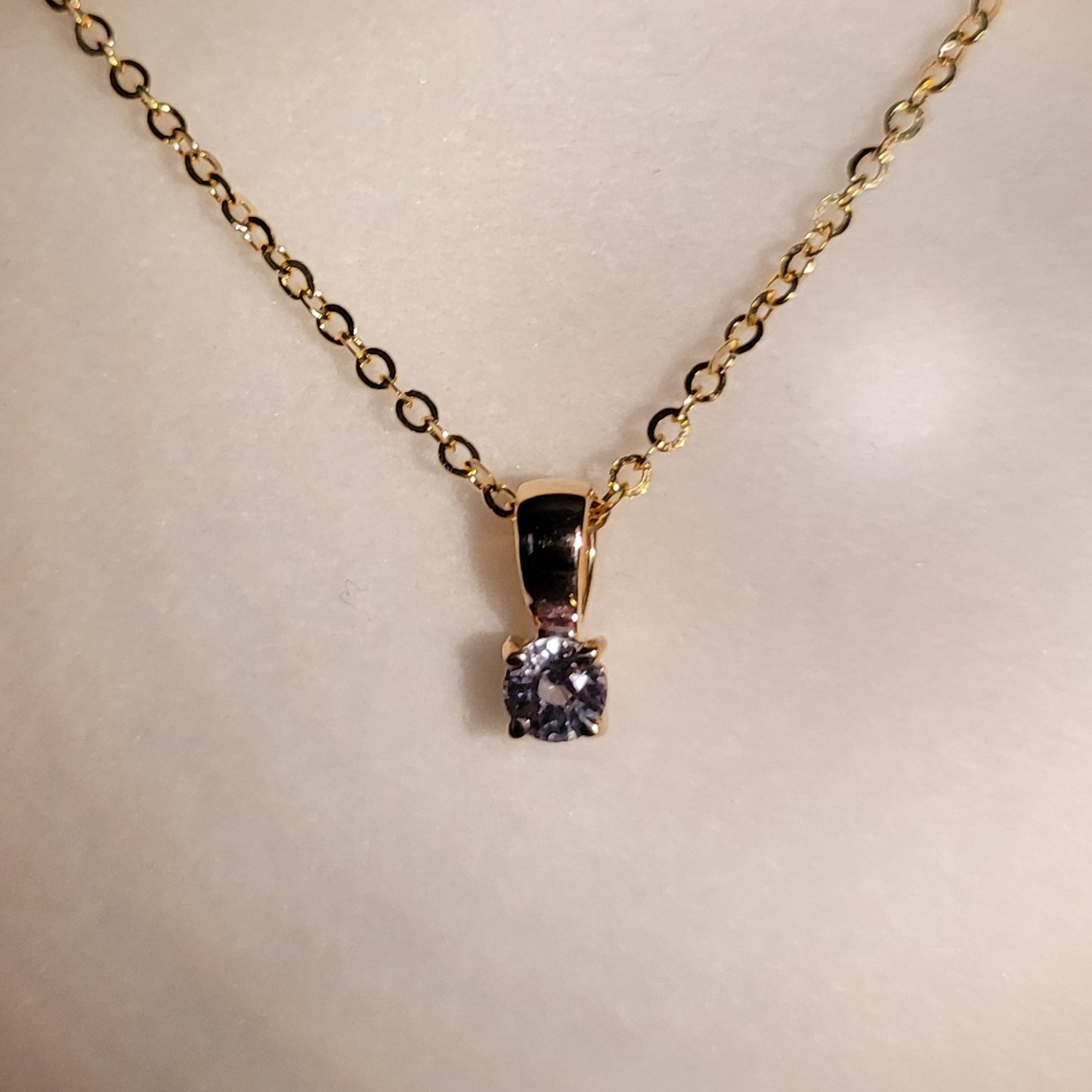 photo of colour shift of yellow gold alexandrite pendant in gray background