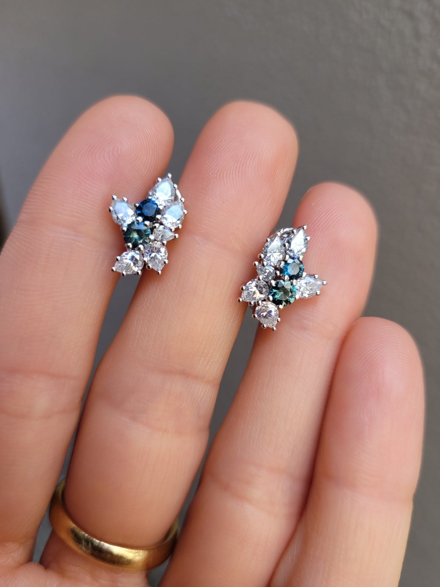 Australian Teal Sapphire & Moissanite Cluster Earrings held between fingers