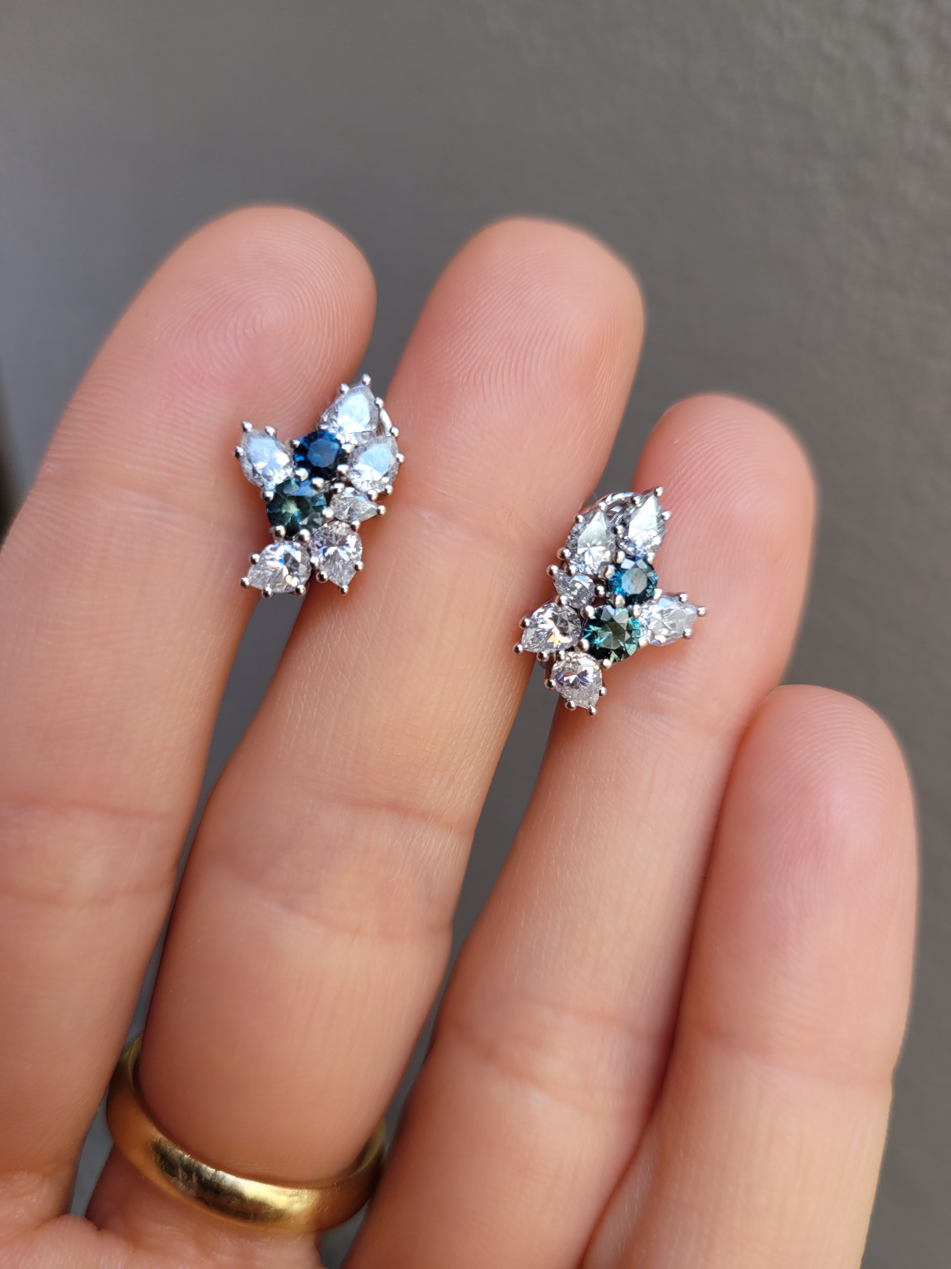 Australian Teal Sapphire & Moissanite Cluster Earrings held between fingers