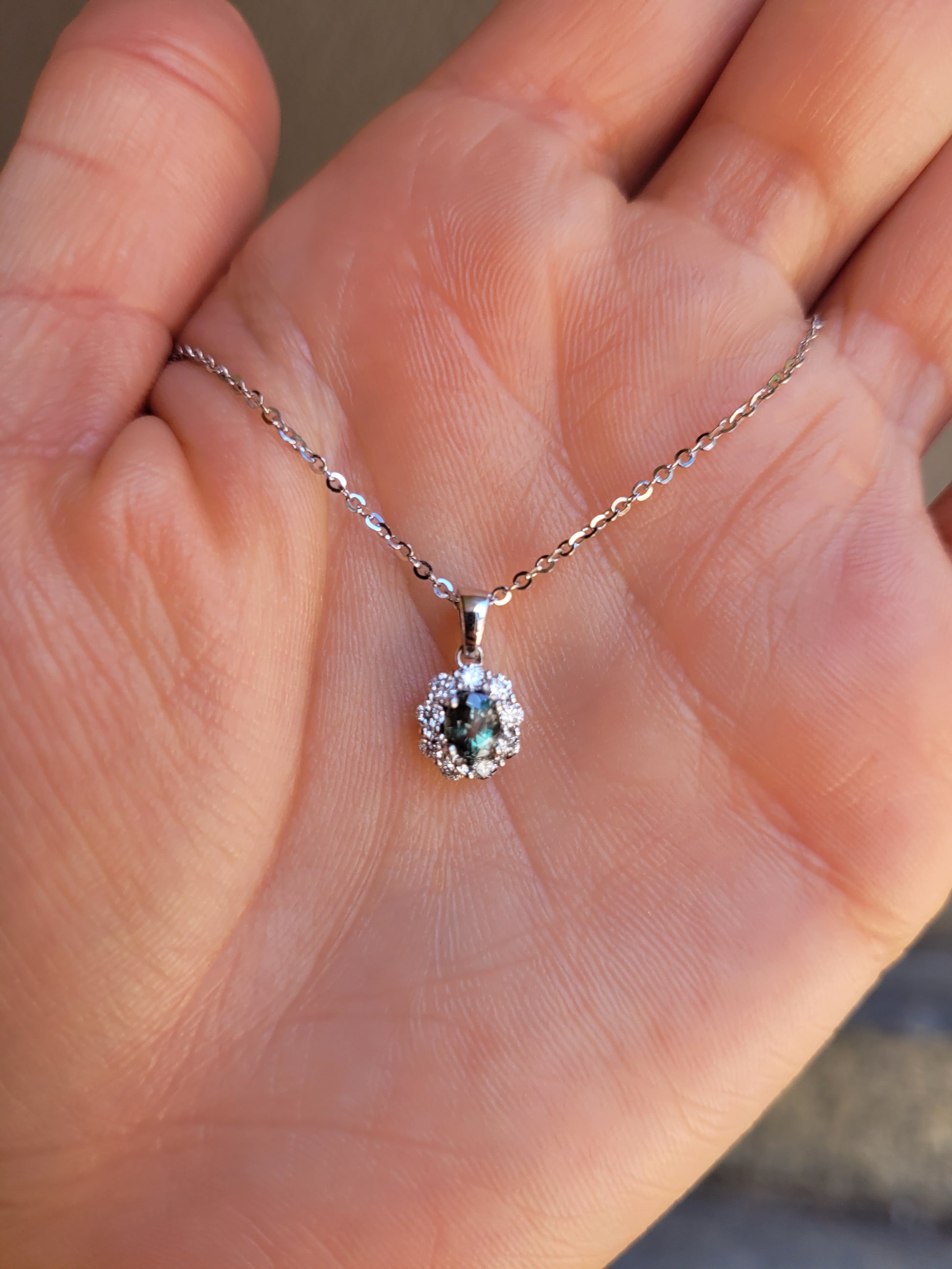 front view of Natural Alexandrite Halo Pendant 0.43ct Oval Cut in Platinum 950 held in a hand
