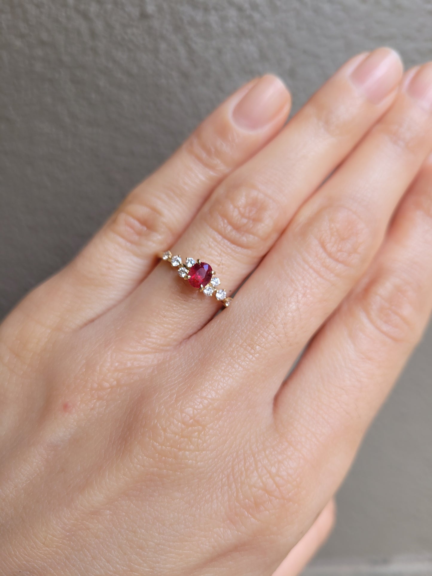 hand wearing ruby and diamonds gold ring in yellow gold in neutral background