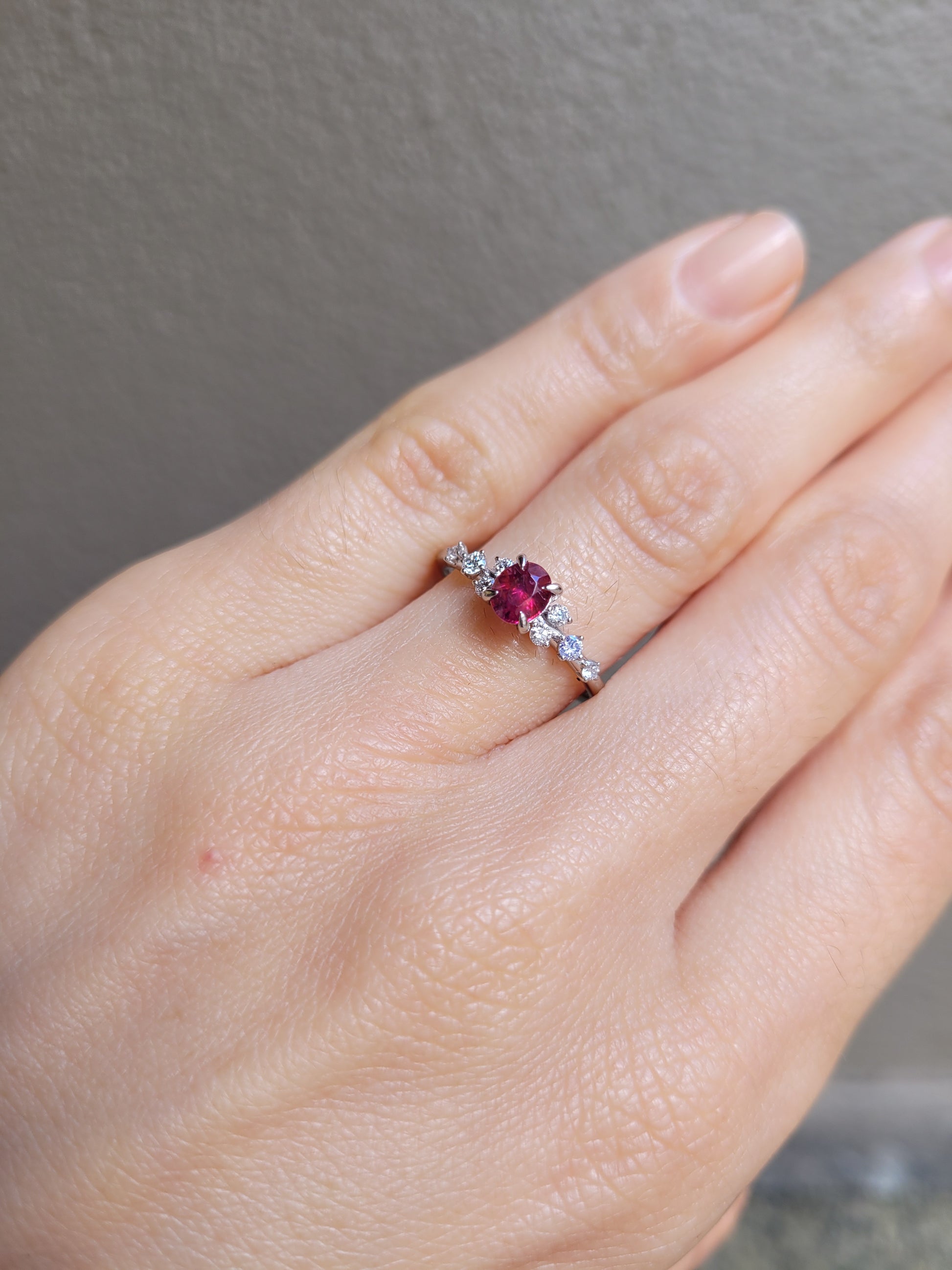view on hand of natural ruby and diamond ring in platinum 950 in neutral background

