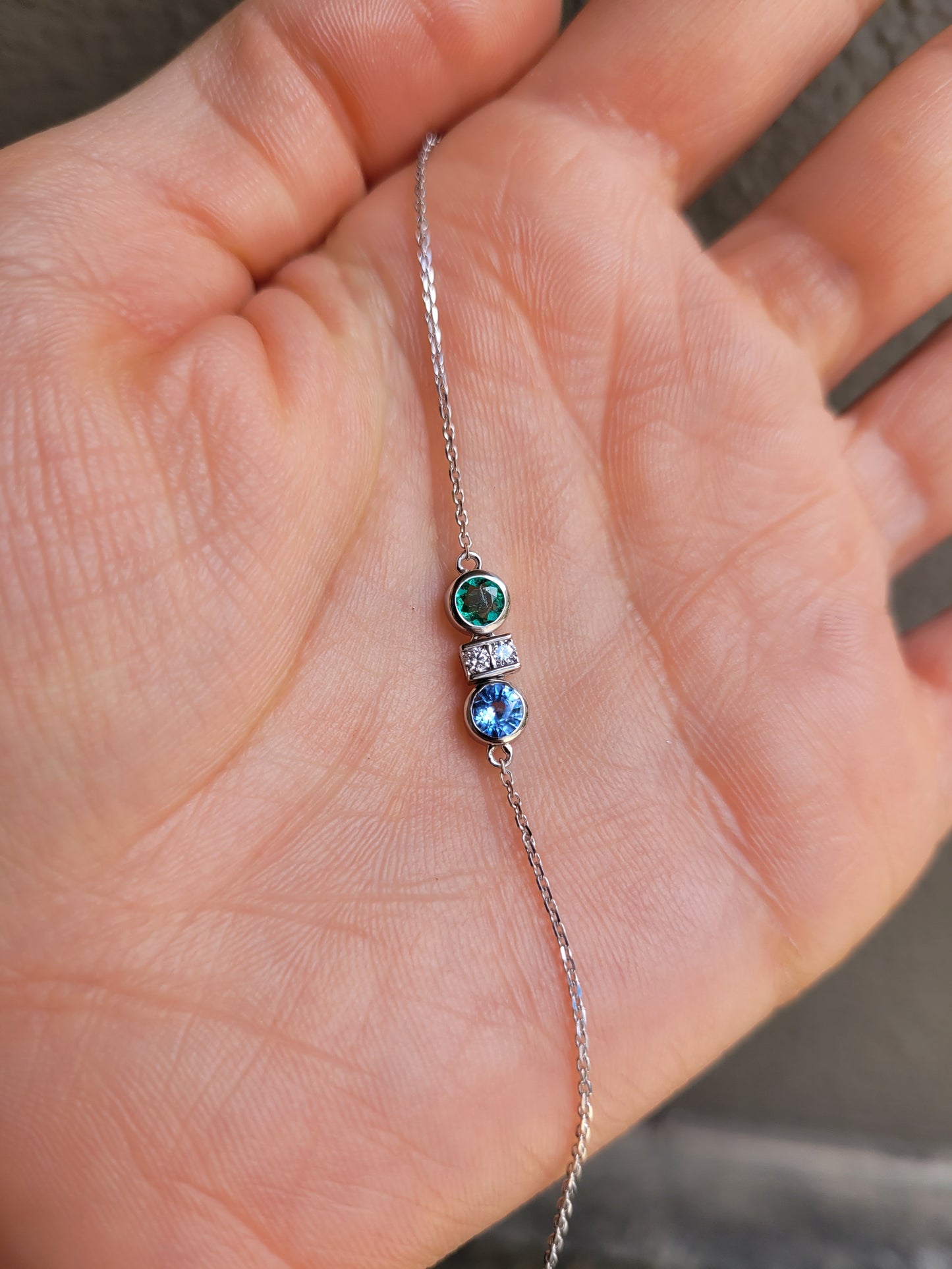 photo of Colombian Emerald, Diamond and Blue Sapphire Bracelet in Platinum 950 held in a hand