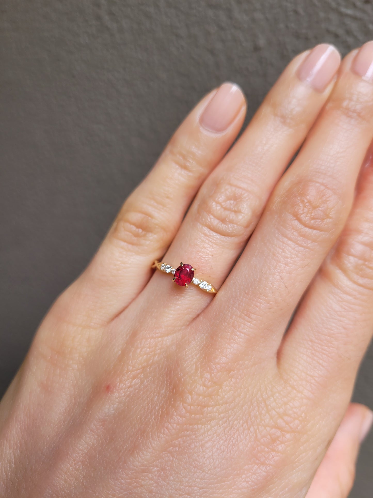 view of a Natural Ruby & Diamond Twisted Band Ring in 18K Yellow Gold worn on a hand in neutral background