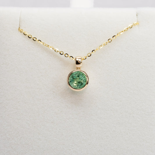 Colombian Emerald Bezel Set Pendant in 18K Yellow Gold with chain in white background
