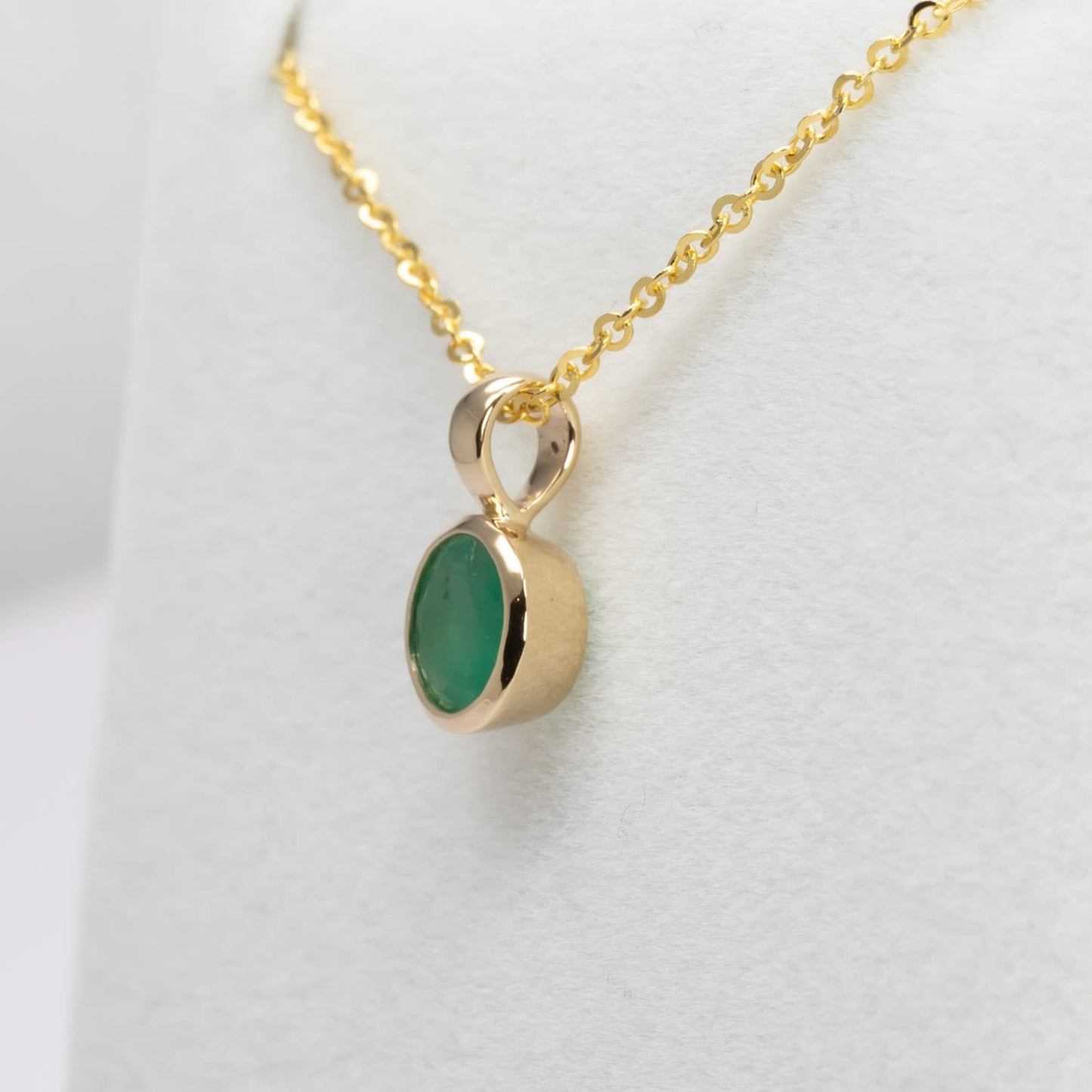 side view of Round Colombian Emerald Bezel Set Pendant in 18K Yellow Gold – 0.62ct in white background