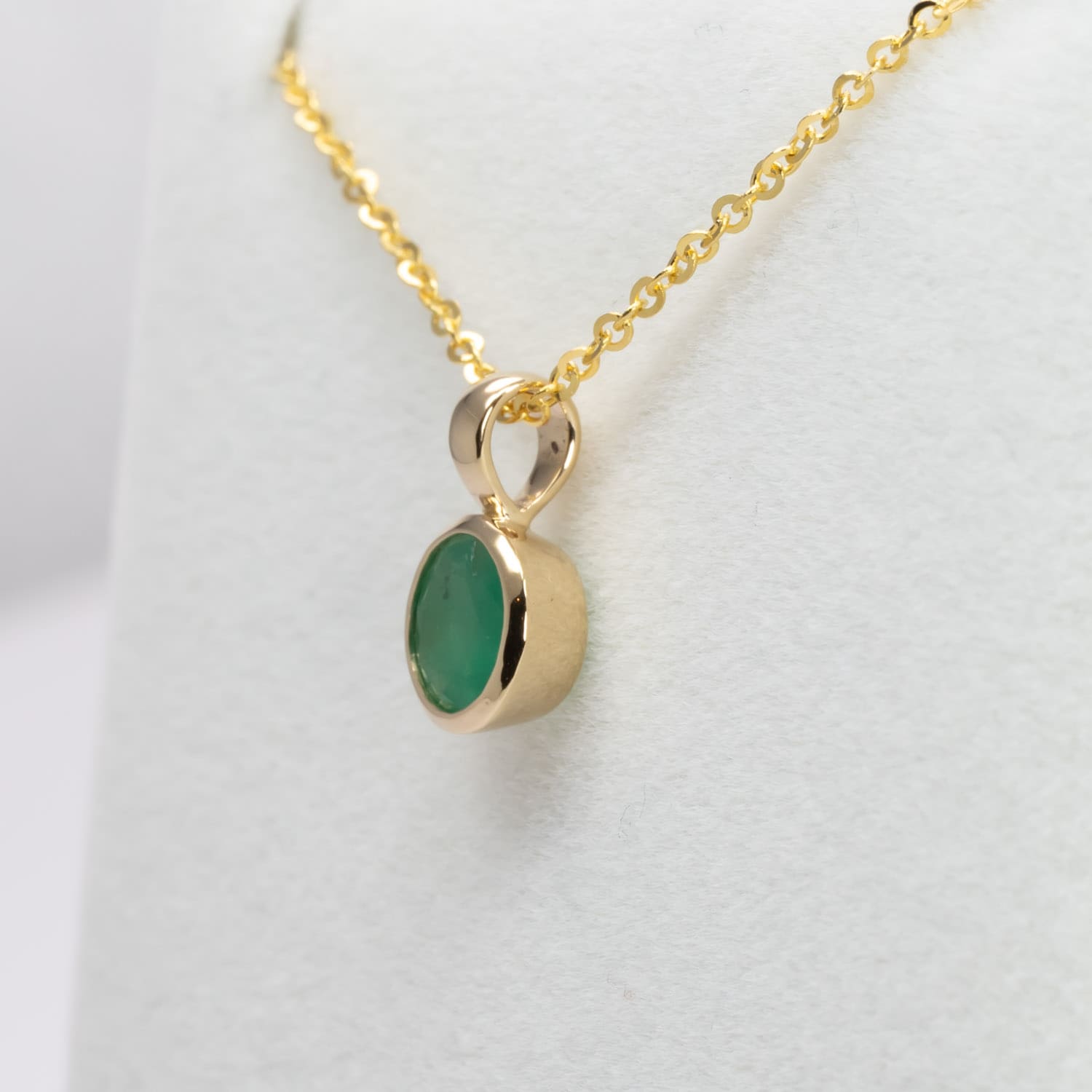 side view of Round Colombian Emerald Bezel Set Pendant in 18K Yellow Gold – 0.62ct in white background