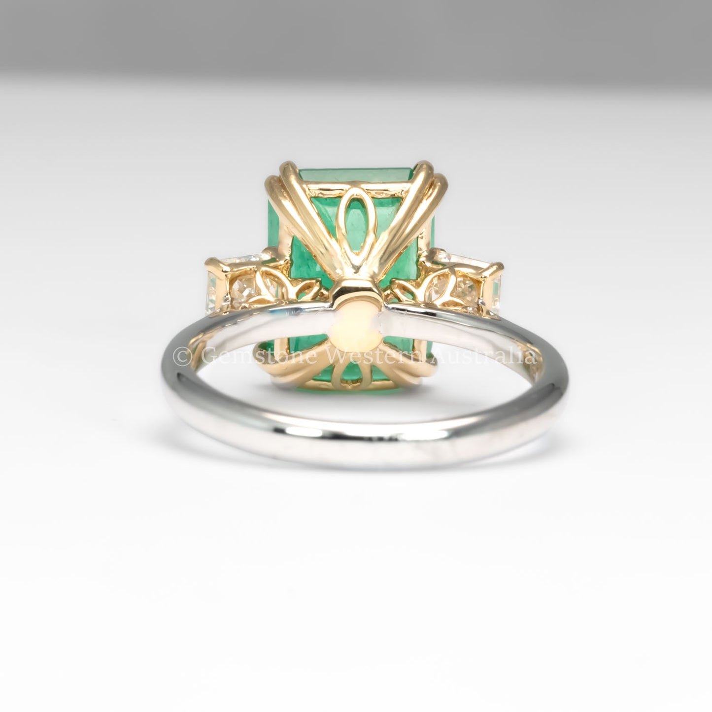 back view of Colombian Emerald and Diamond Ring in 18K Yellow Gold – East West Emerald Cut in neutral background